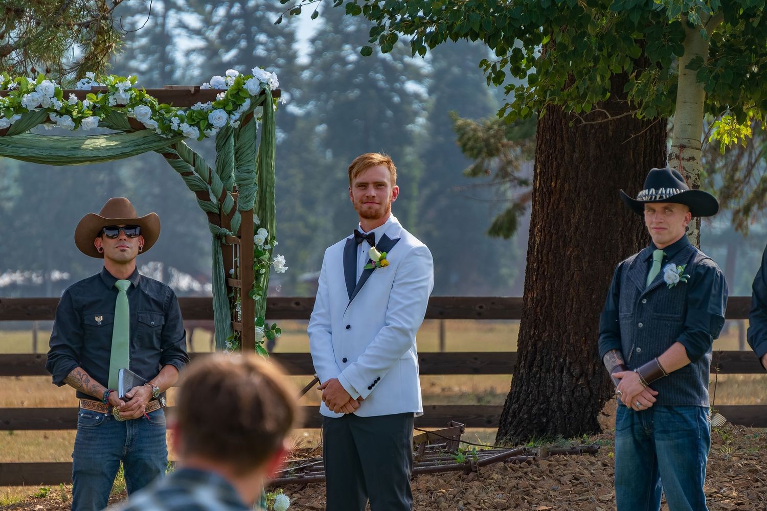 Groomsmen lined up outdoors against a wooded backdrop.