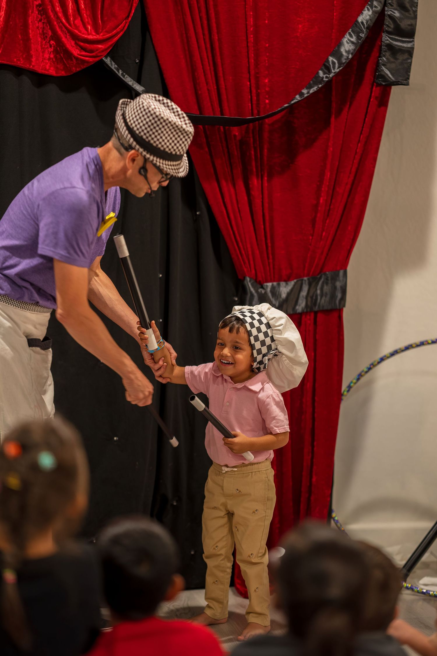 A magic show performance featuring interactive moments with the audience against red theater curtains.
