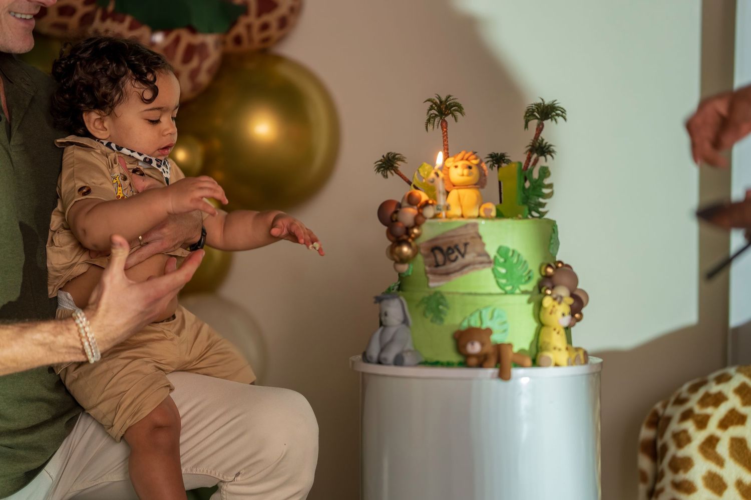 A festive jungle-themed birthday celebration with a green tiered cake and gold balloons.