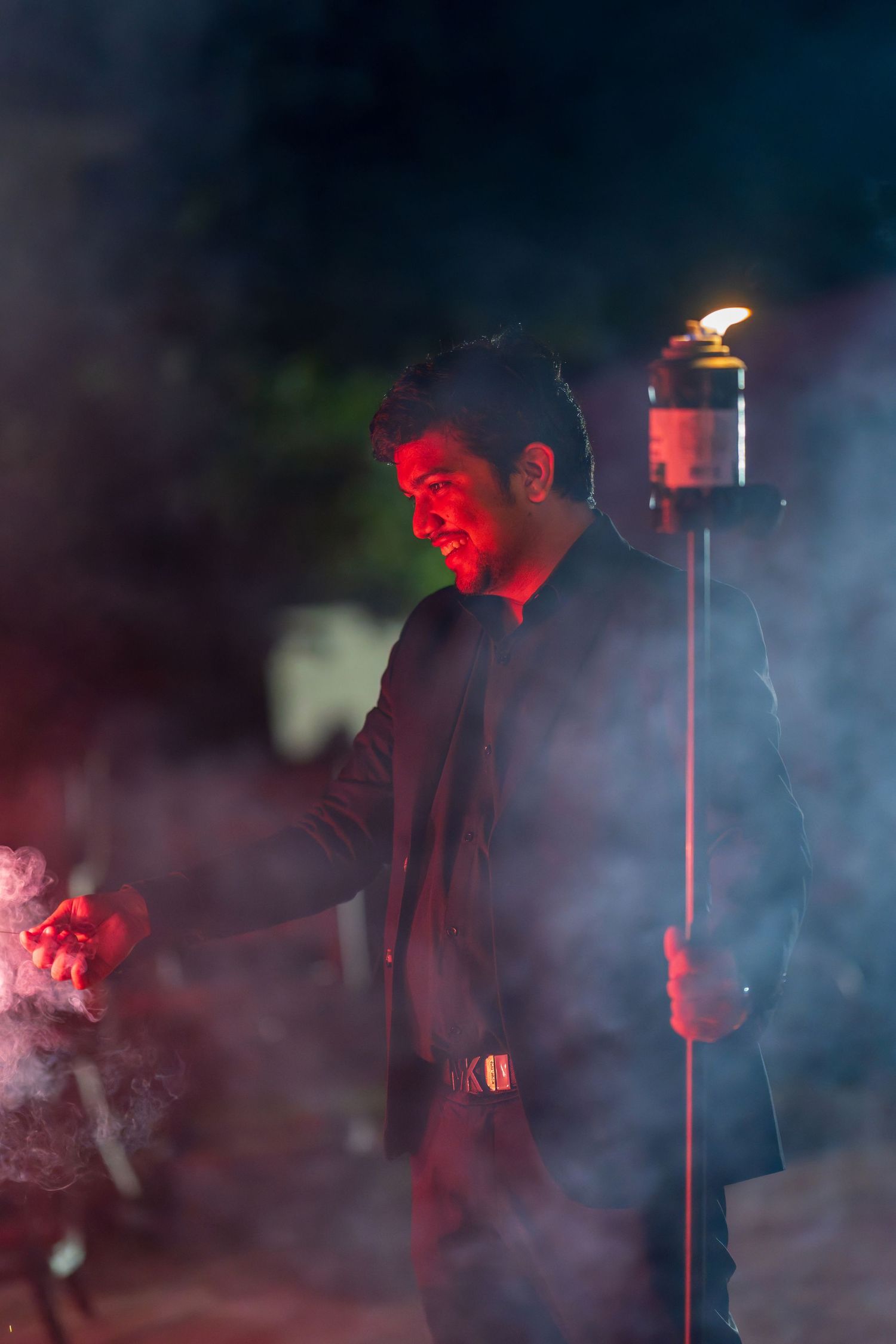 Silhouettes of performers in atmospheric red lighting and smoke effects create a dramatic scene.