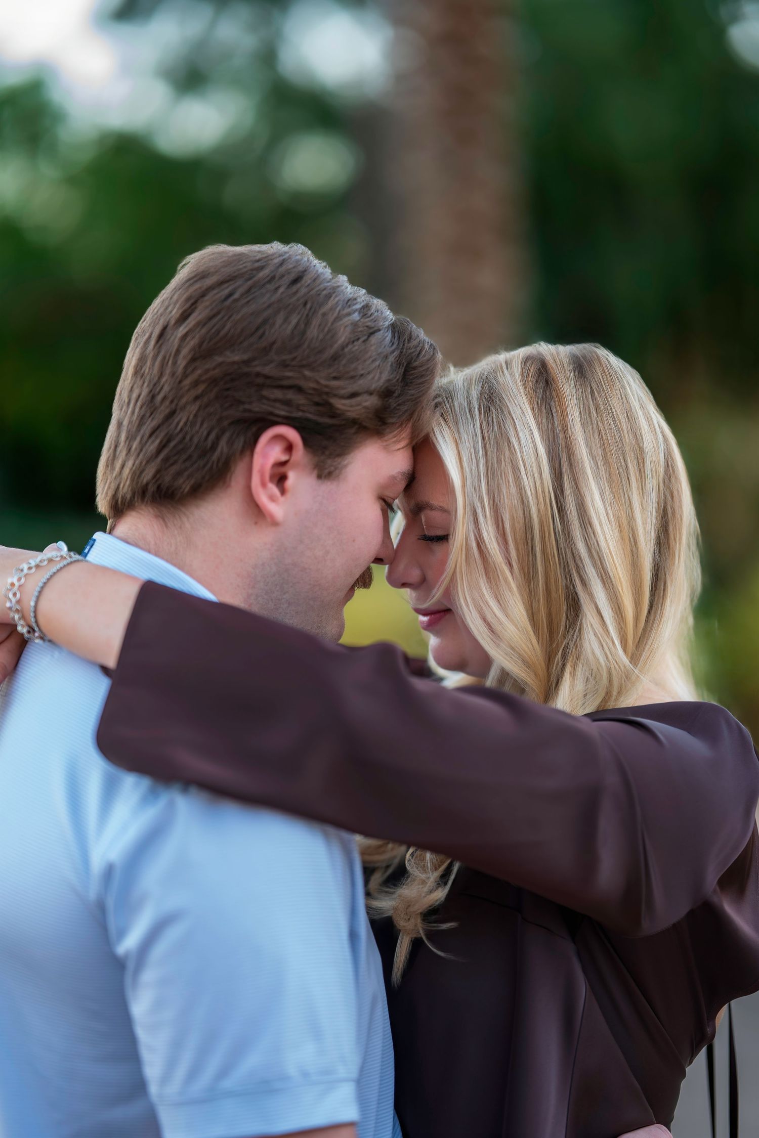 Romantic couple touching foreheads tenderly in an outdoor garden setting during an engagement session.