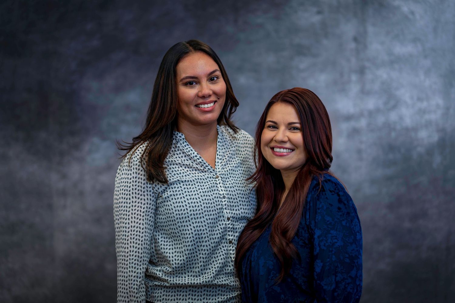 Two people posing together for professional headshots in business attire.