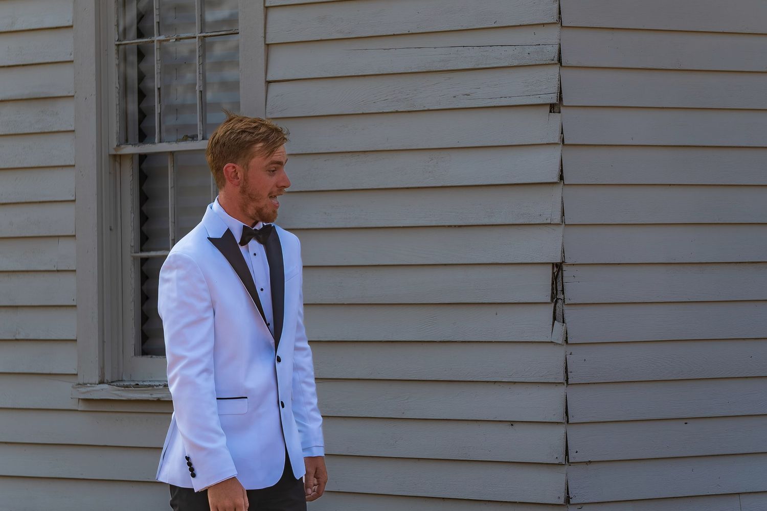 A joyful wedding moment captured against a white siding backdrop.