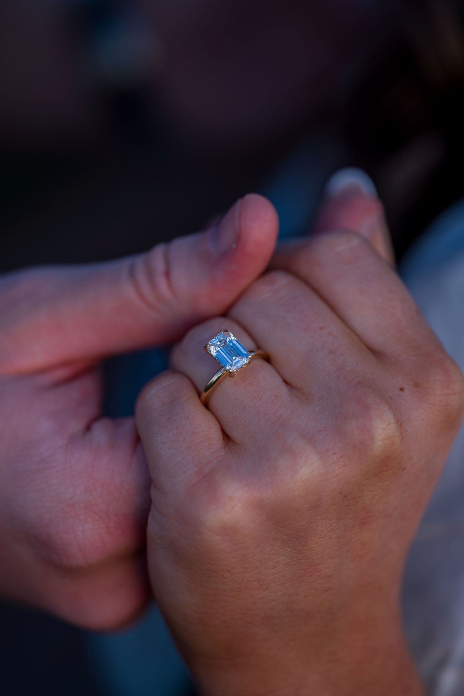 Close-up shot of hands displaying a sparkling engagement ring.