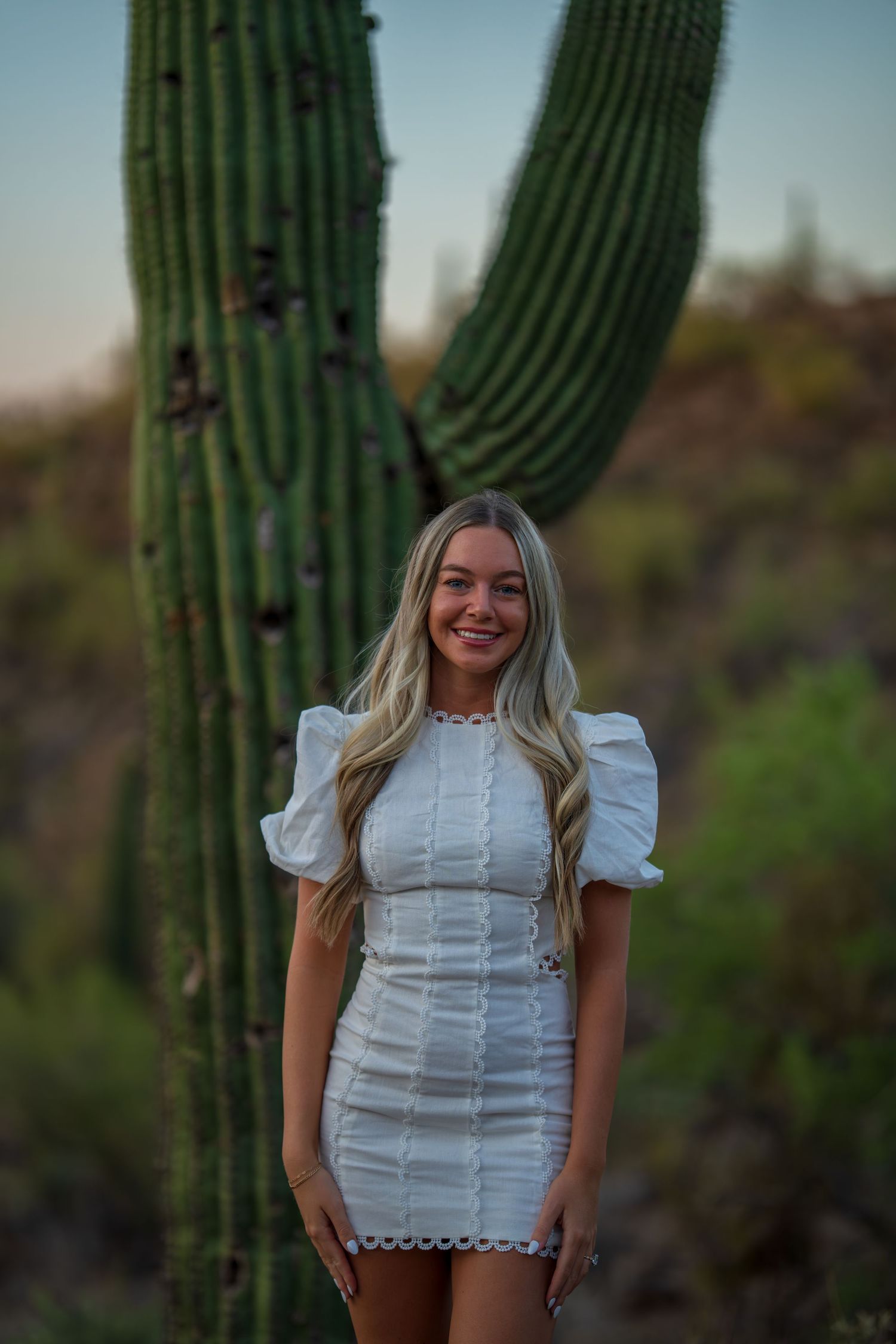 Elegant white dress with puffy sleeves styled against a majestic saguaro cactus backdrop in the Arizona desert.