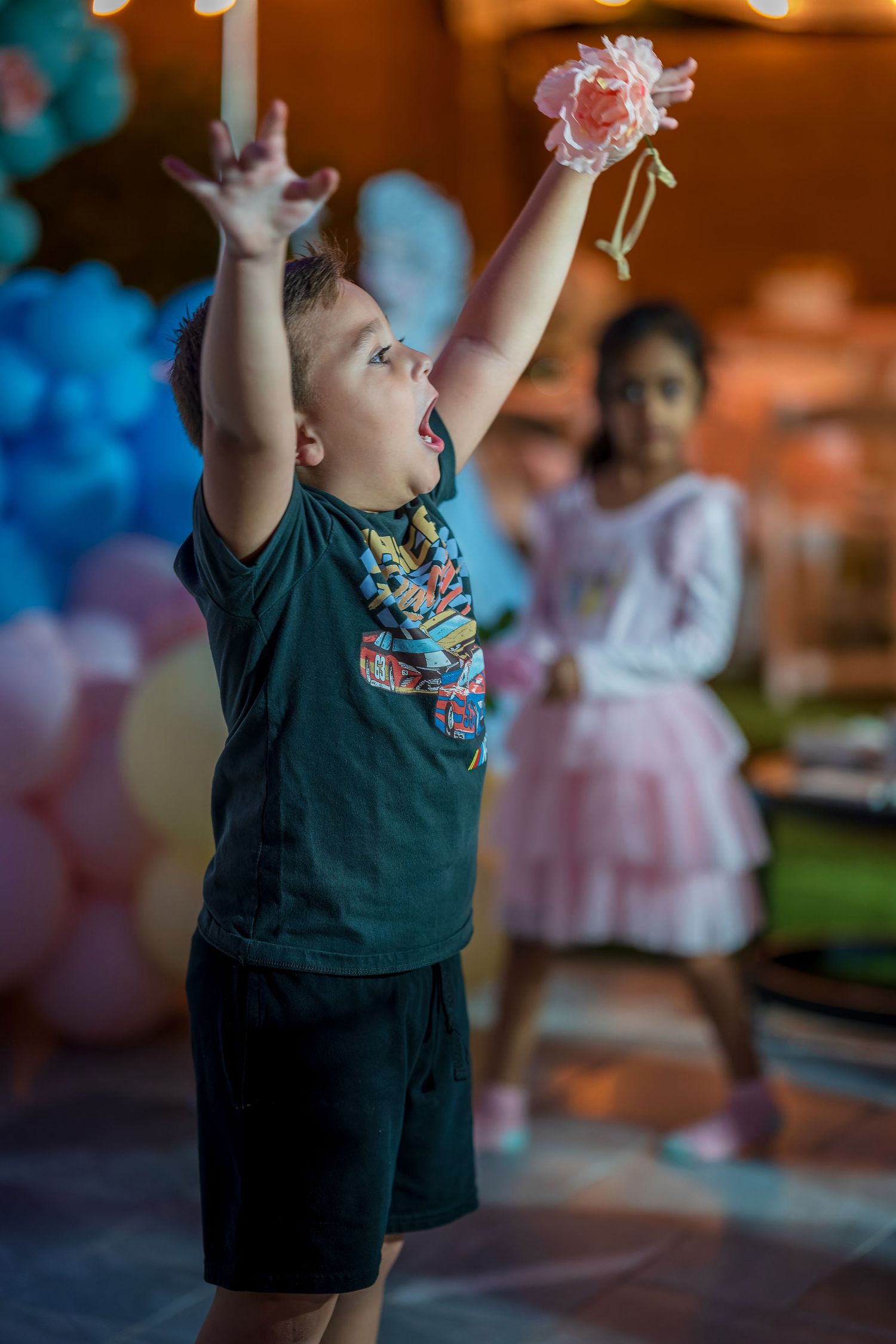 A child in dark clothing raises their arms during an indoor performance.