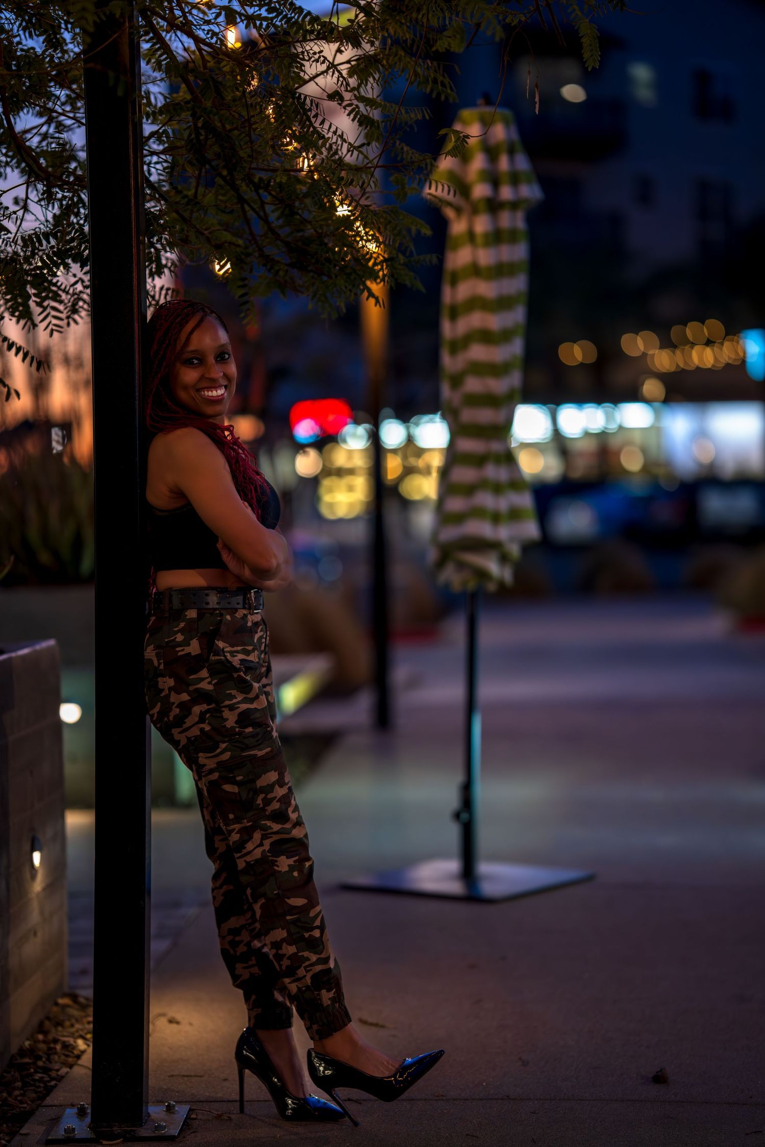 Urban nighttime portrait with city lights and trees creating ambient atmosphere.