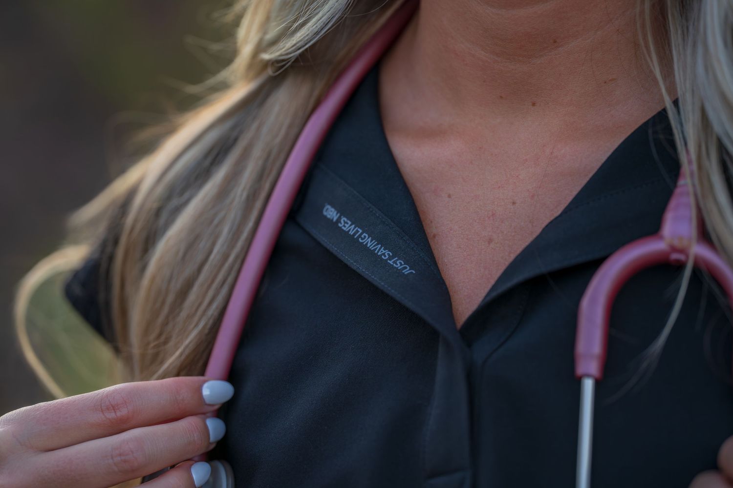 Medical professional with stethoscope stands in front of desert mountain backdrop.