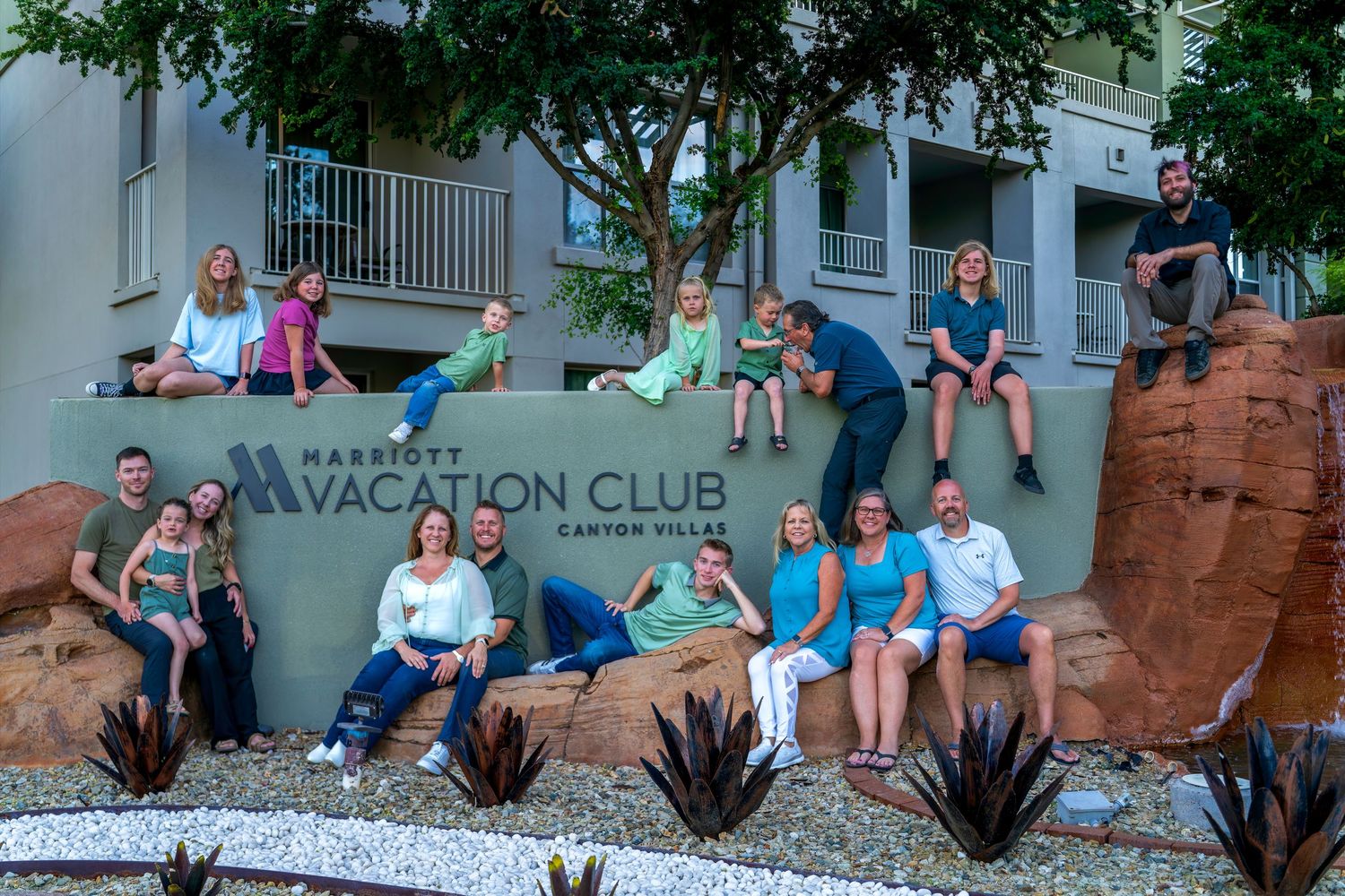 Large family group posing together on rocks beside a Marriott Vacation Club Canyon Villas sign.