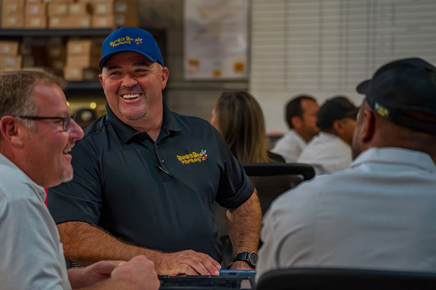 Casual workplace gathering with employees seated around tables.