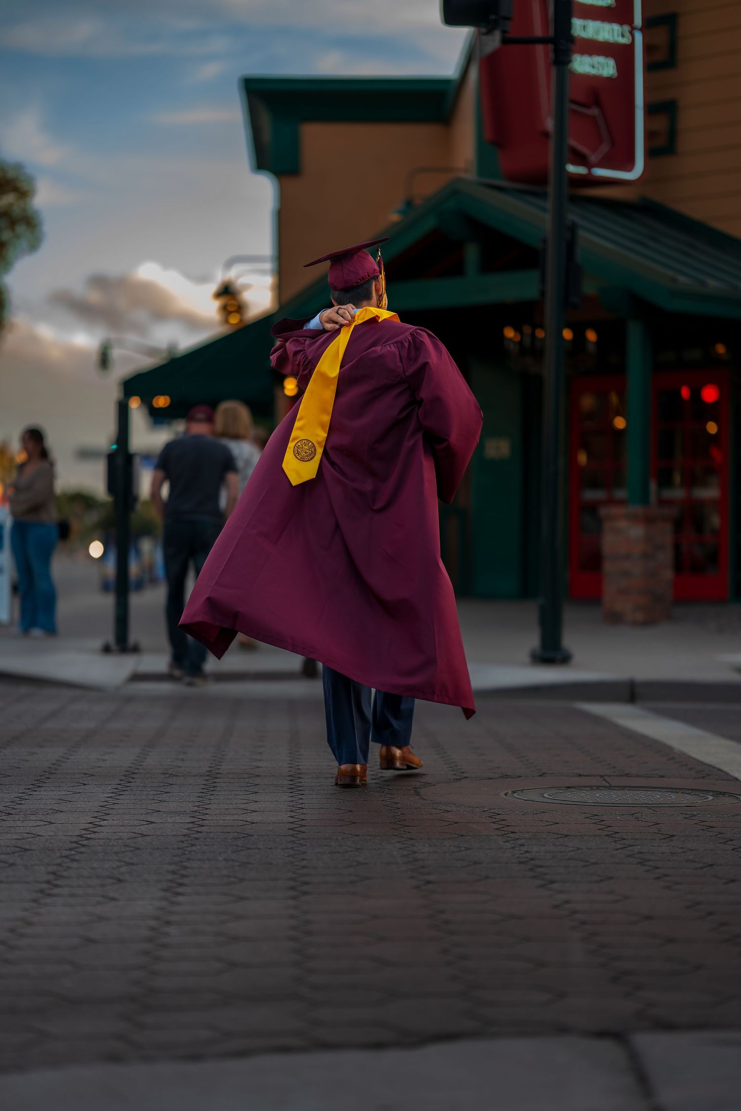 Artistic low-angle shot of graduation gown flowing in evening light.
