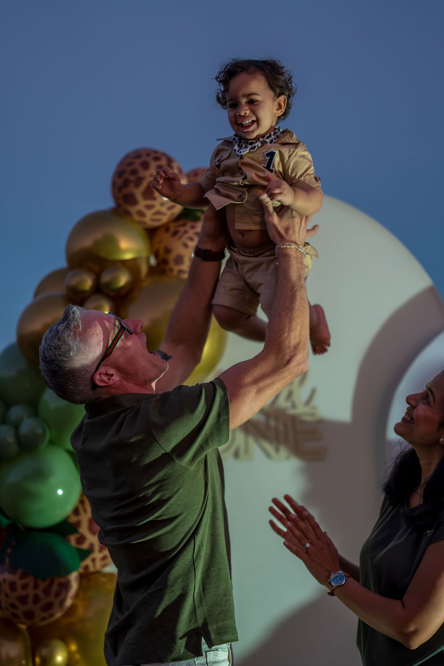 Playful interaction at a party decorated with safari animals and metallic balloons.