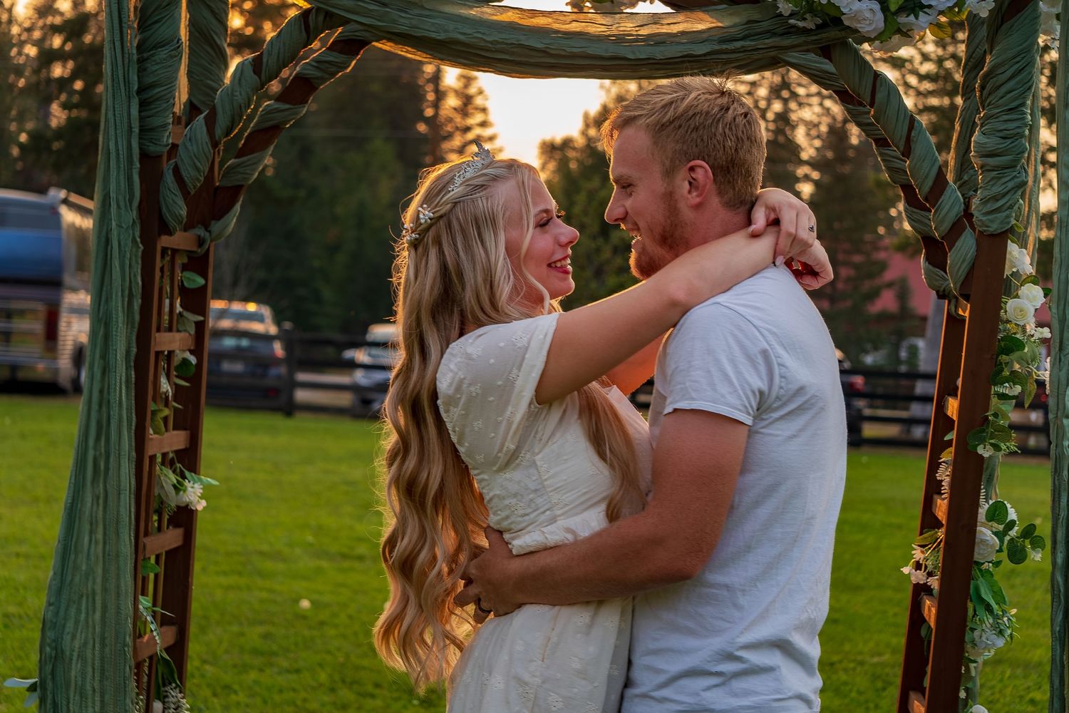 Romantic embrace under garden arch during sunset.