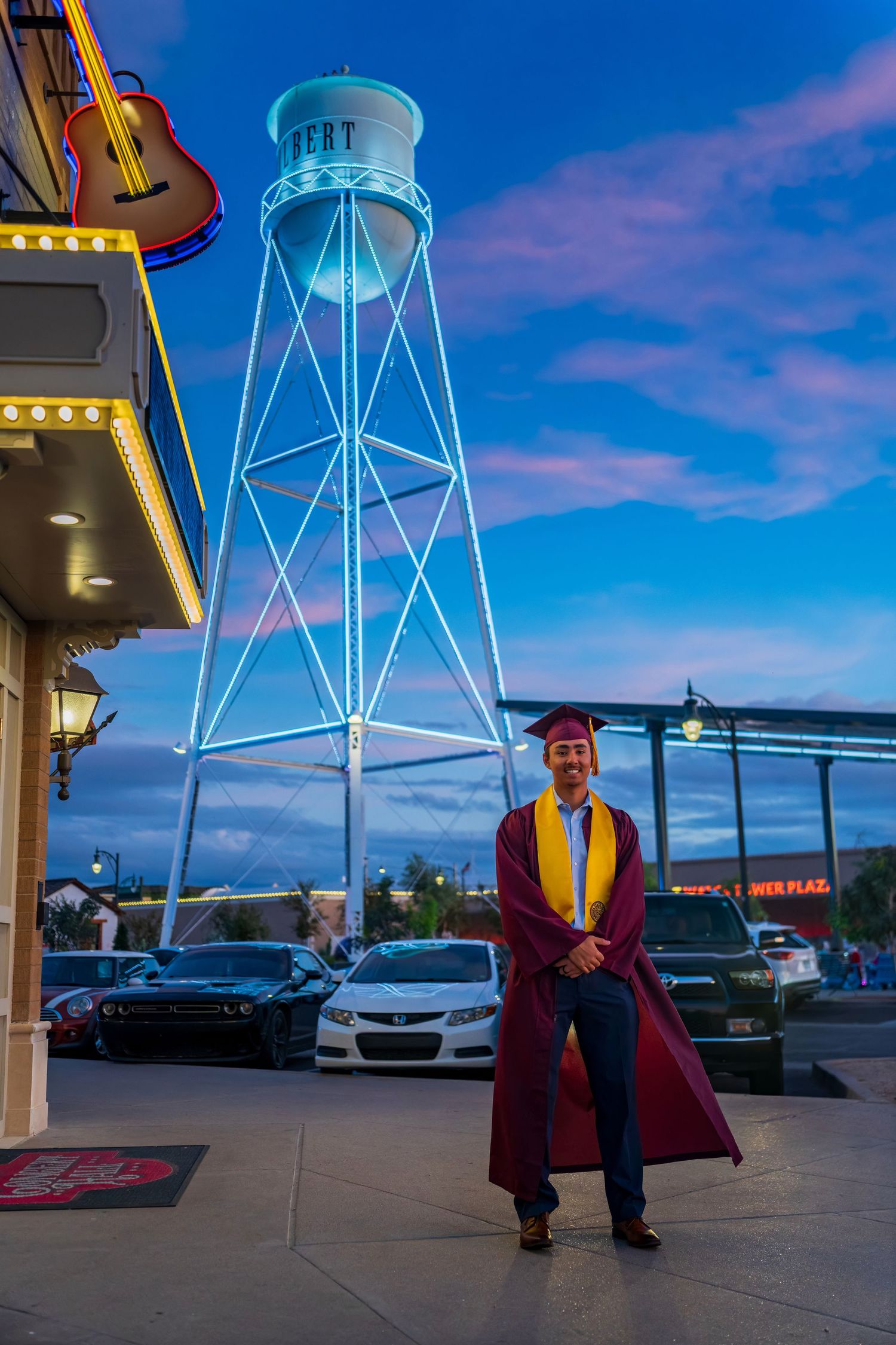 Graduation portraits taken near illuminated water tower at dusk.