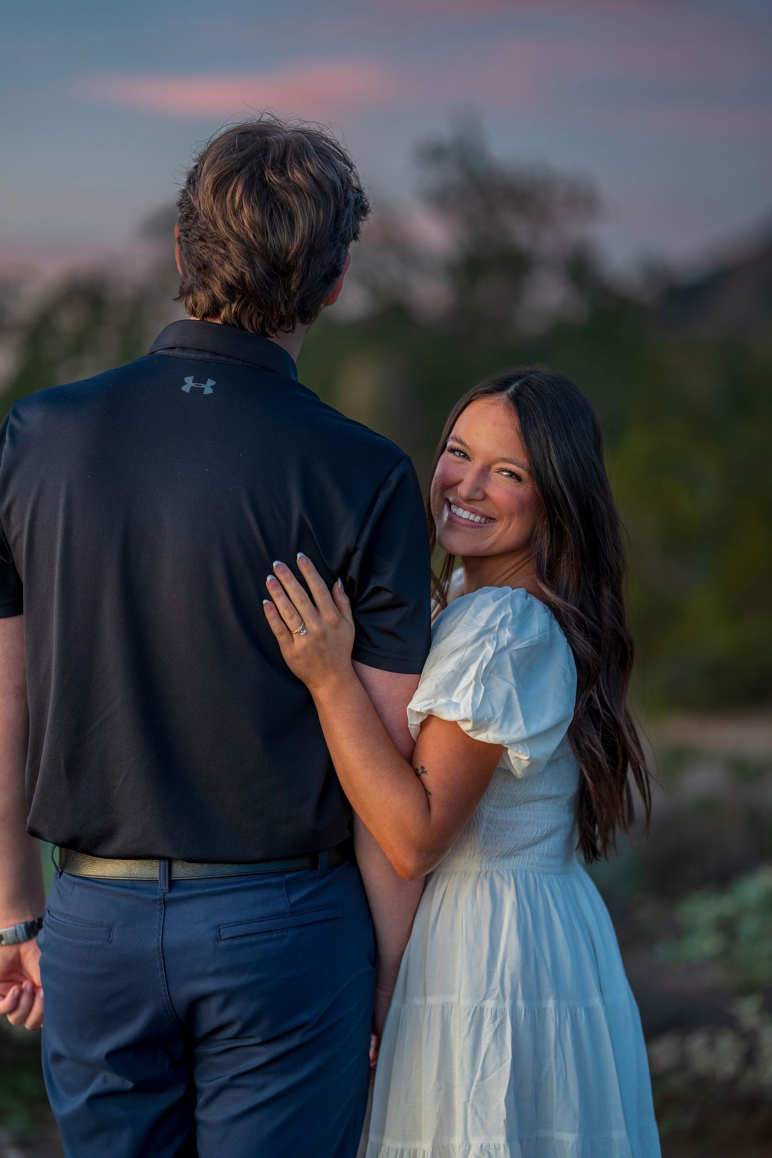 A couple shares loving glances during their sunset engagement session in the desert.