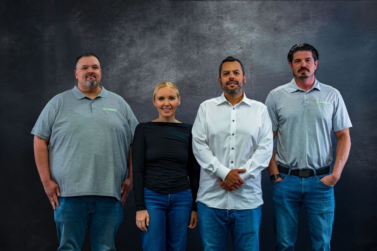 Professional team members in various colored polo shirts standing against a gray backdrop.