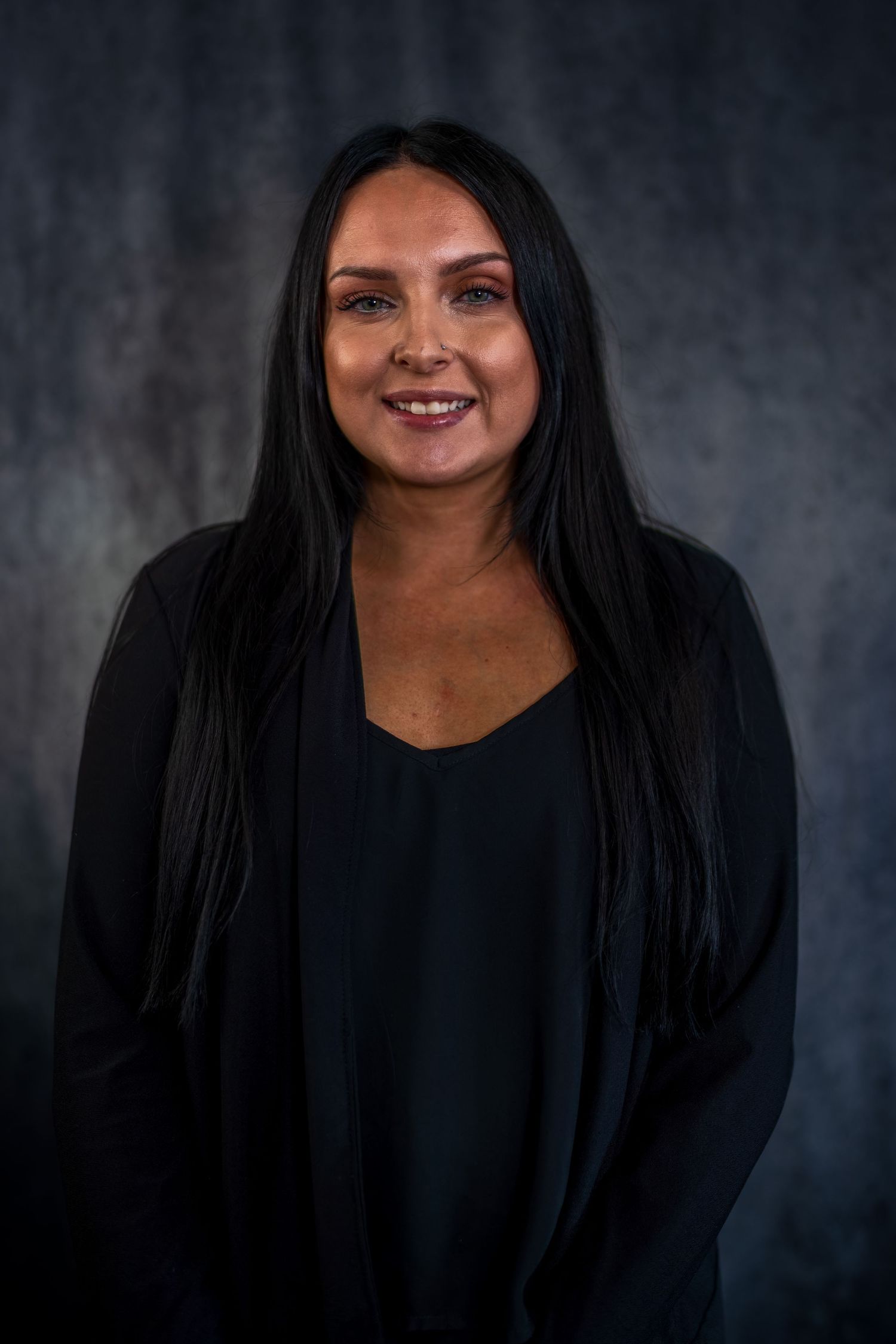 Business portrait series in black outfit showing natural expressions against dark backdrop.