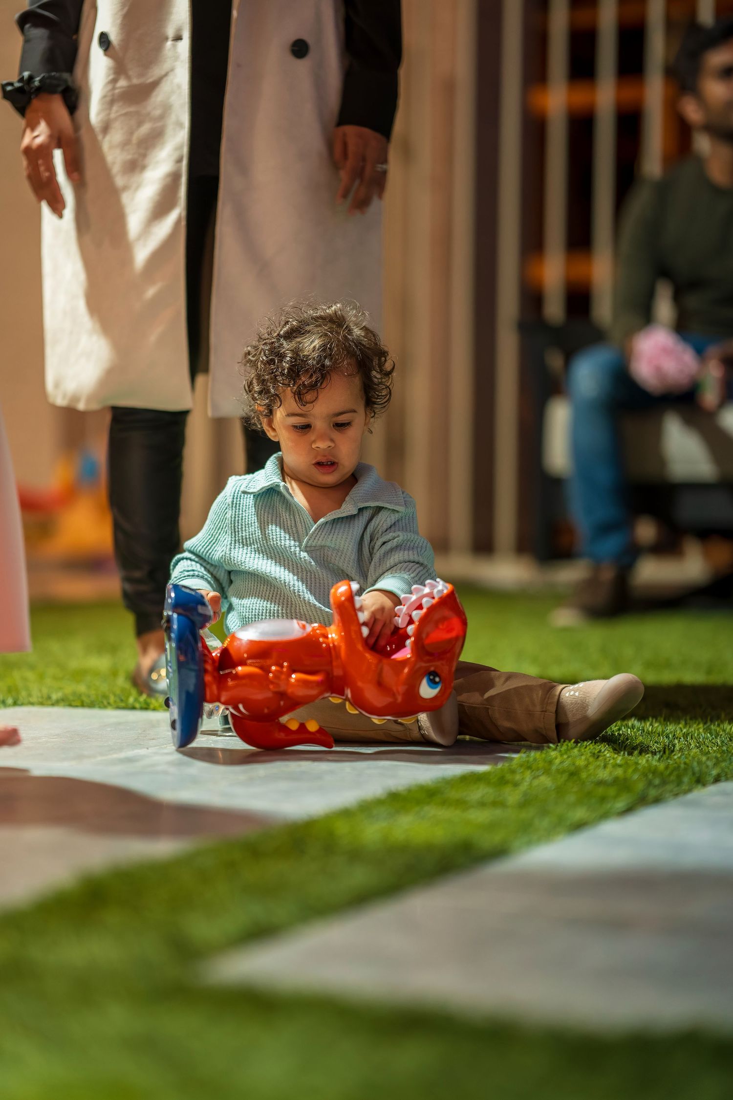 A toddler plays on artificial grass at a decorated party venue.
