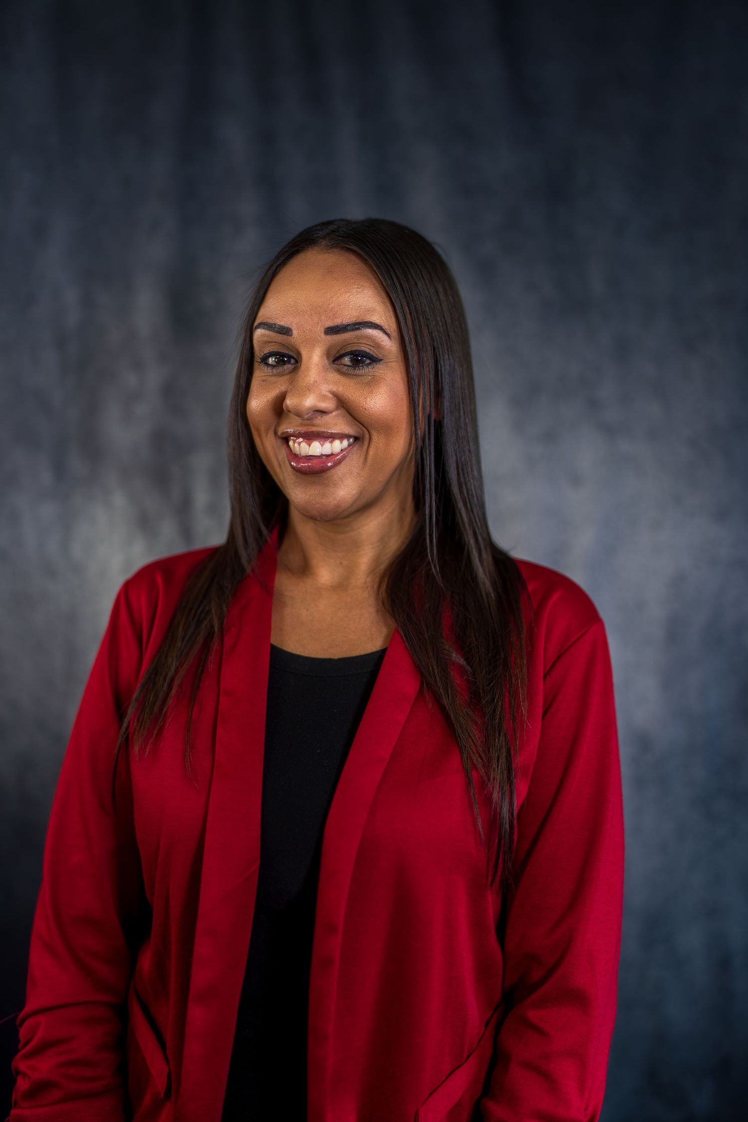 Business headshot series in red blazer showing warm expressions against dark background.