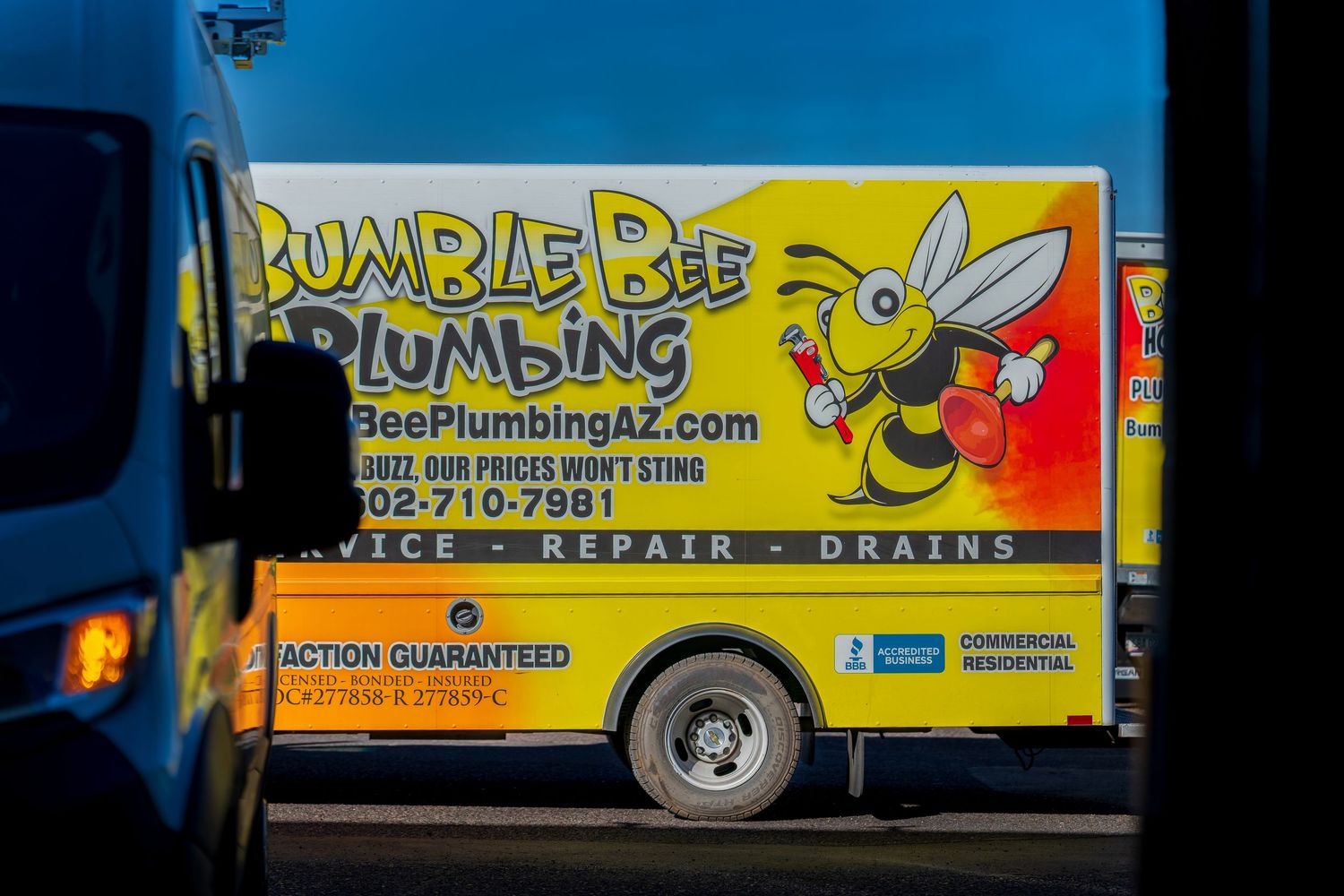 Fleet of bright yellow Bumble Bee Plumbing service vehicles parked in a row.