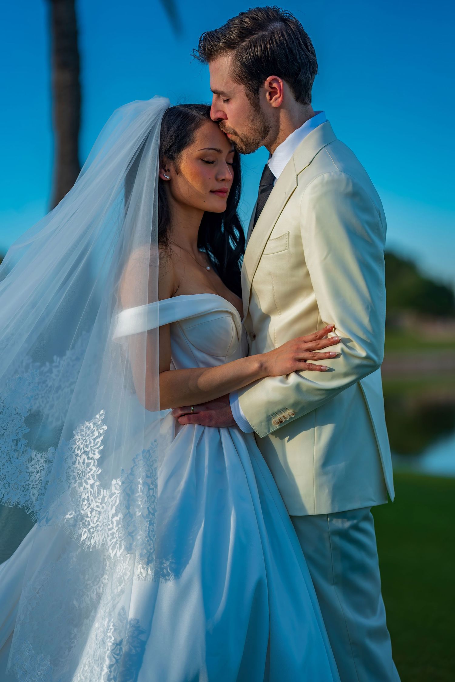 An intimate wedding moment captured with a beautiful white dress and flowing veil detail.