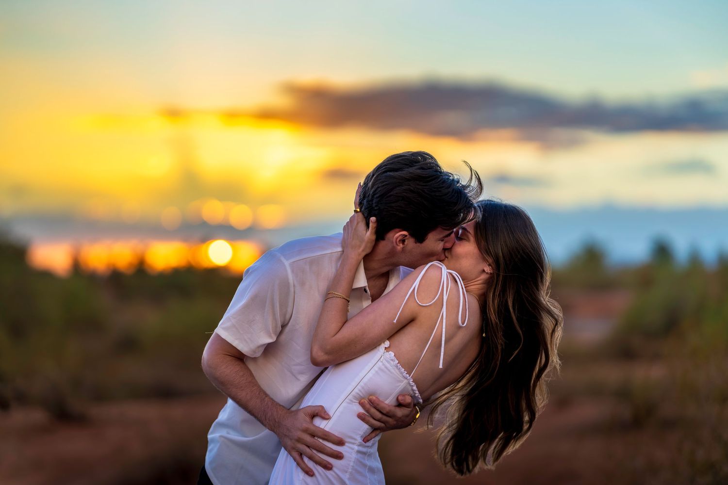 Romantic couple embracing during golden hour sunset in desert setting.