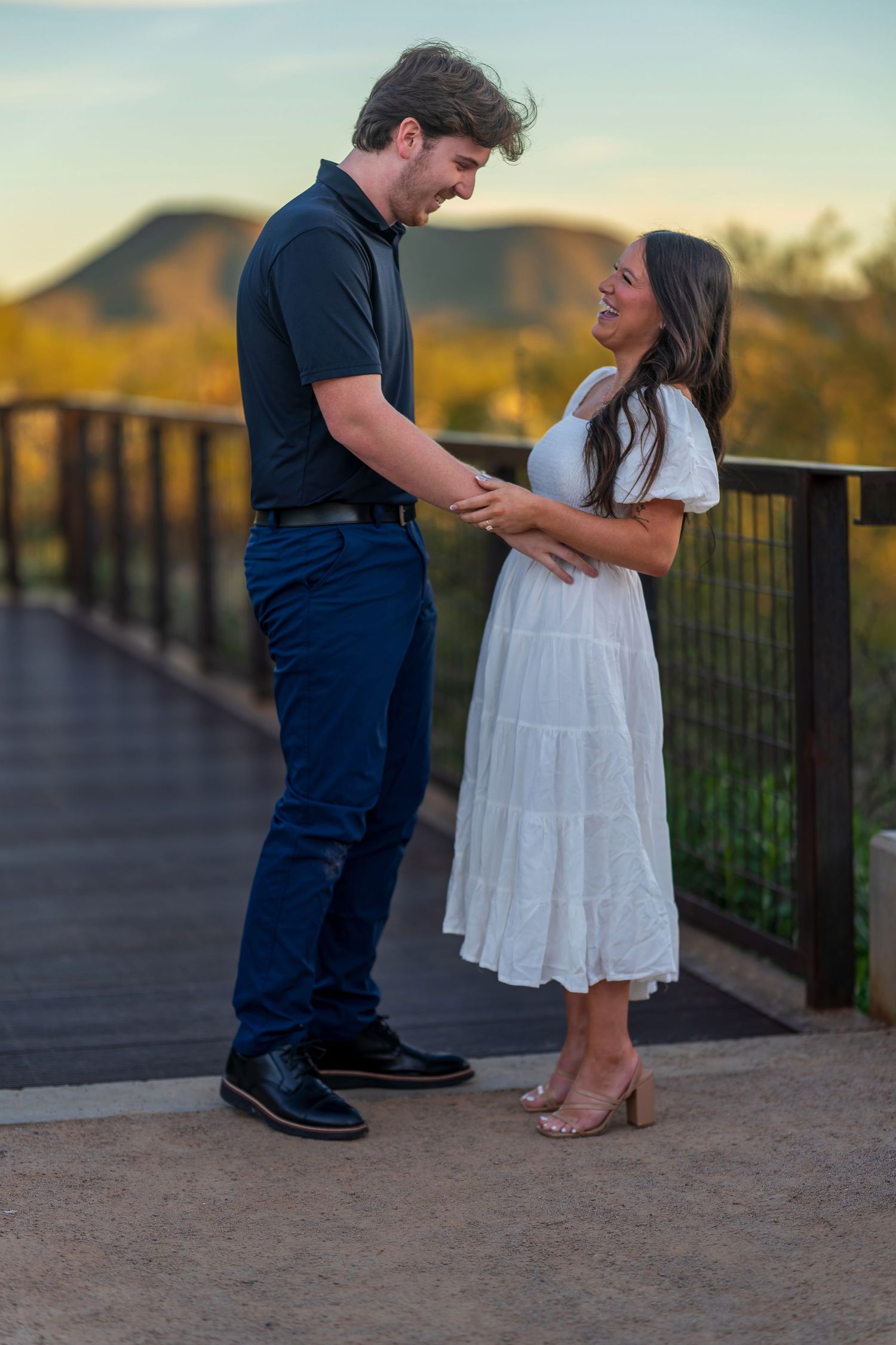 A couple shares an emotional moment on a desert overlook during golden hour.