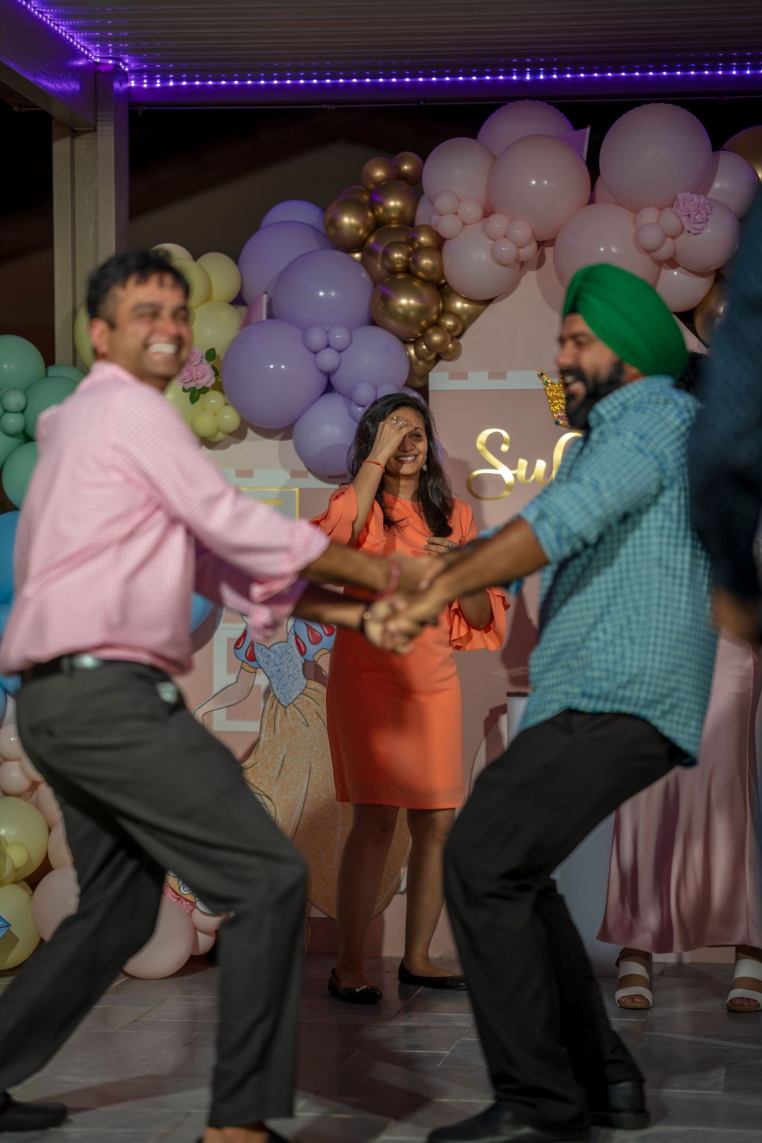 Group dancing together at a celebration with pastel balloon backdrop.