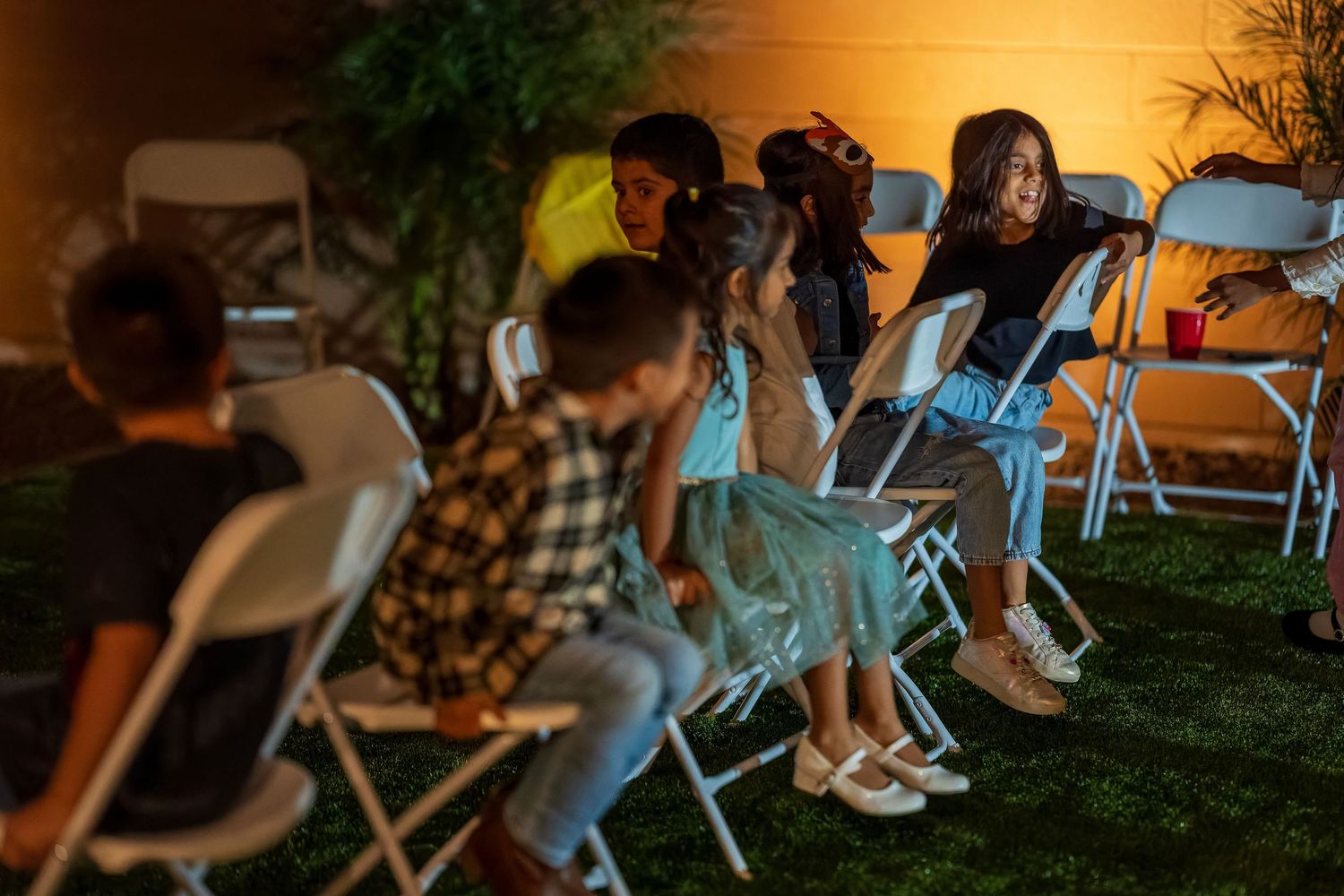 People seated in folding chairs at nighttime outdoor event.