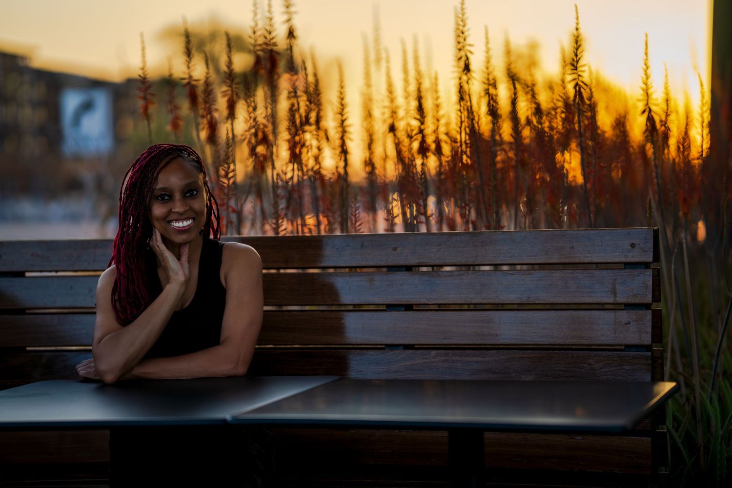 A sunset portrait session on a wooden bench with dramatic golden hour lighting.