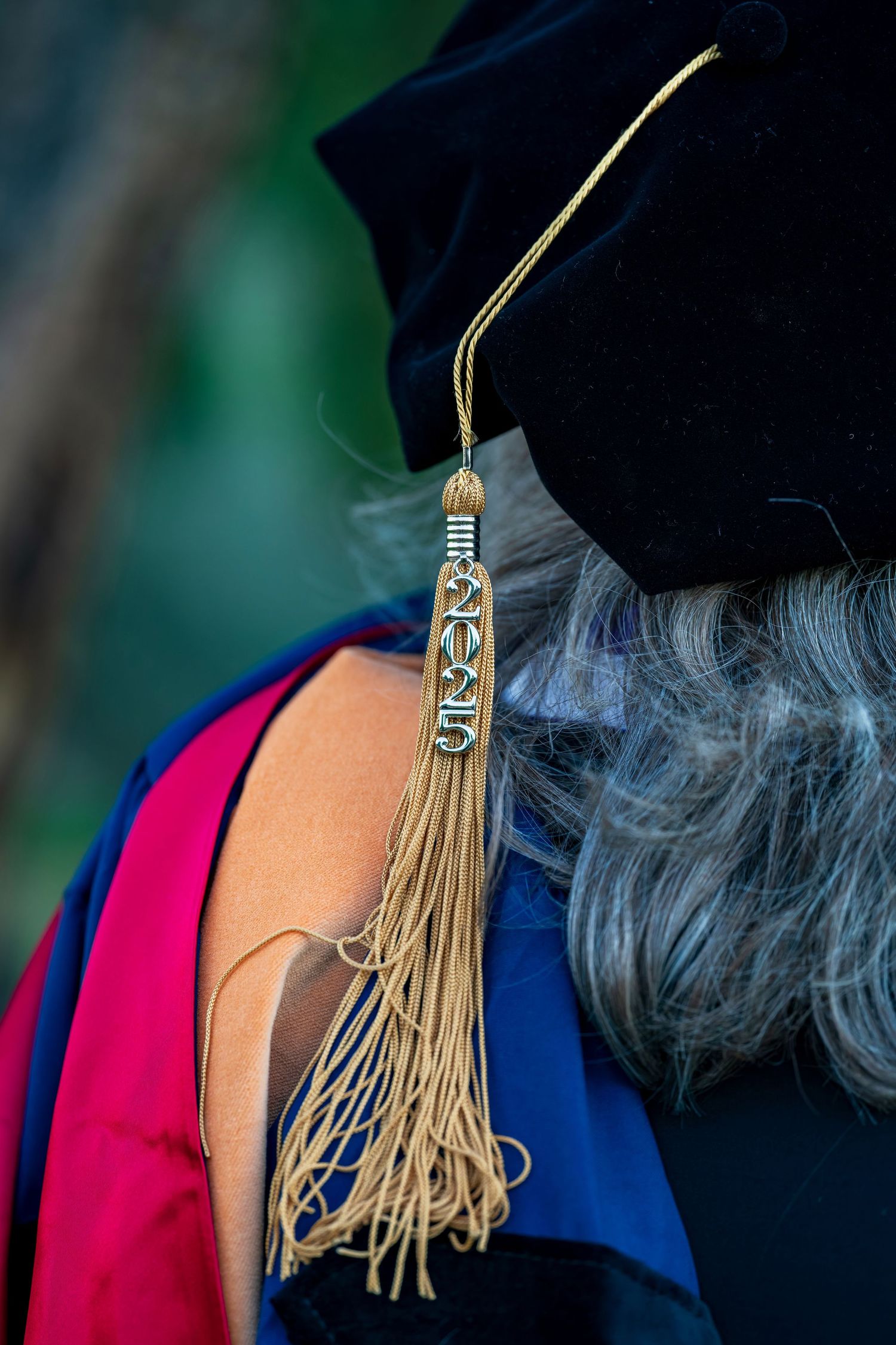 Close-up of graduation tassel against dark academic regalia.