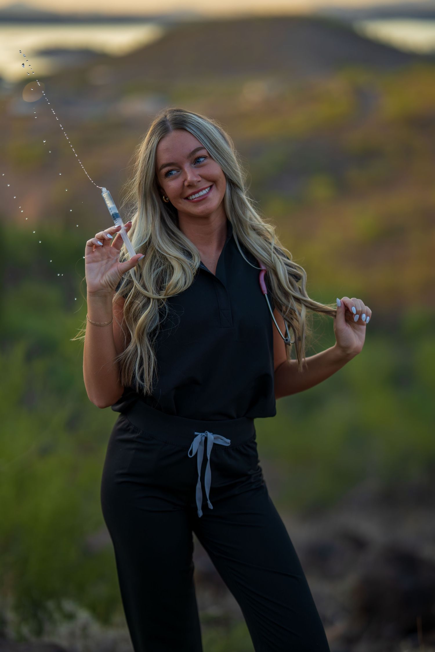 Medical professional in dark scrubs playfully poses during sunset photoshoot in desert setting.