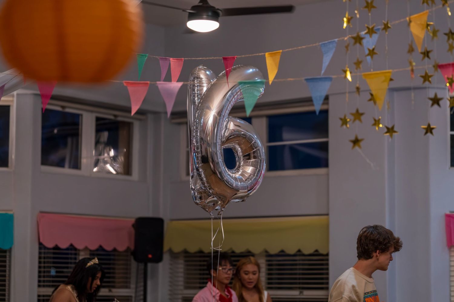 Colorful party bunting and balloons hanging from ceiling at celebration venue.