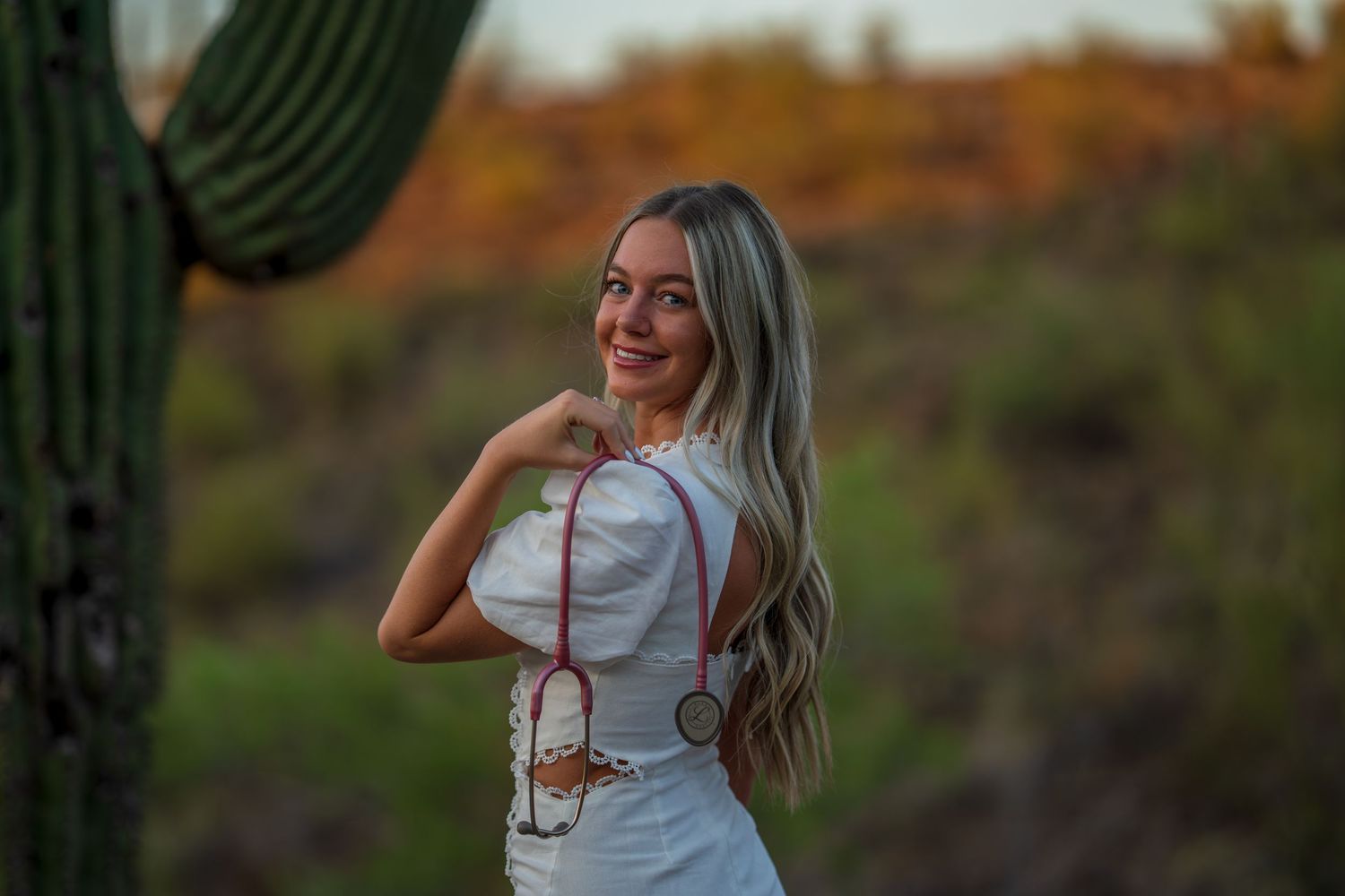White dress with medical accessory styled against desert backdrop with saguaro cactus.