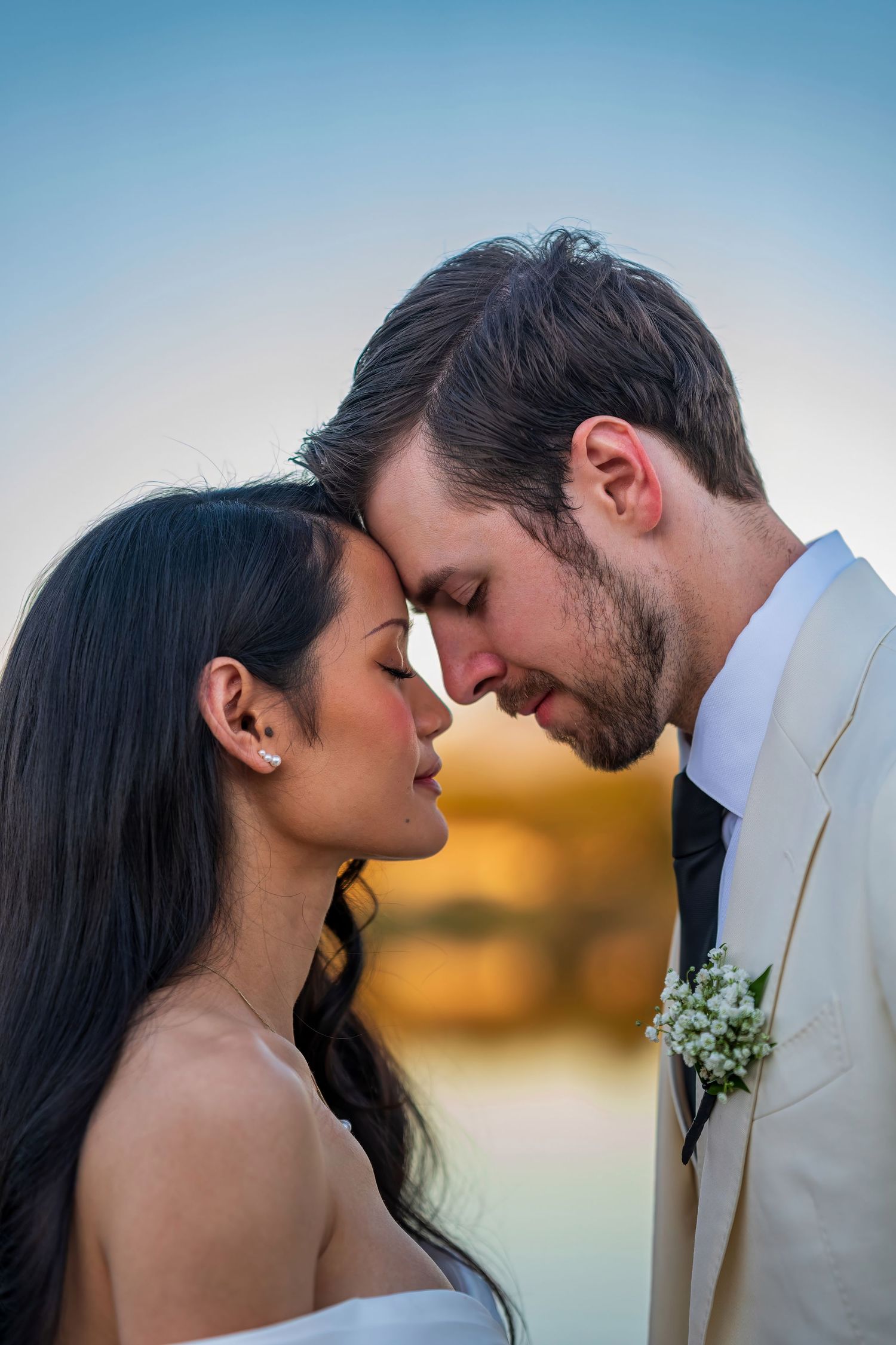 Sunset wedding portrait showing tender moment between newlyweds.