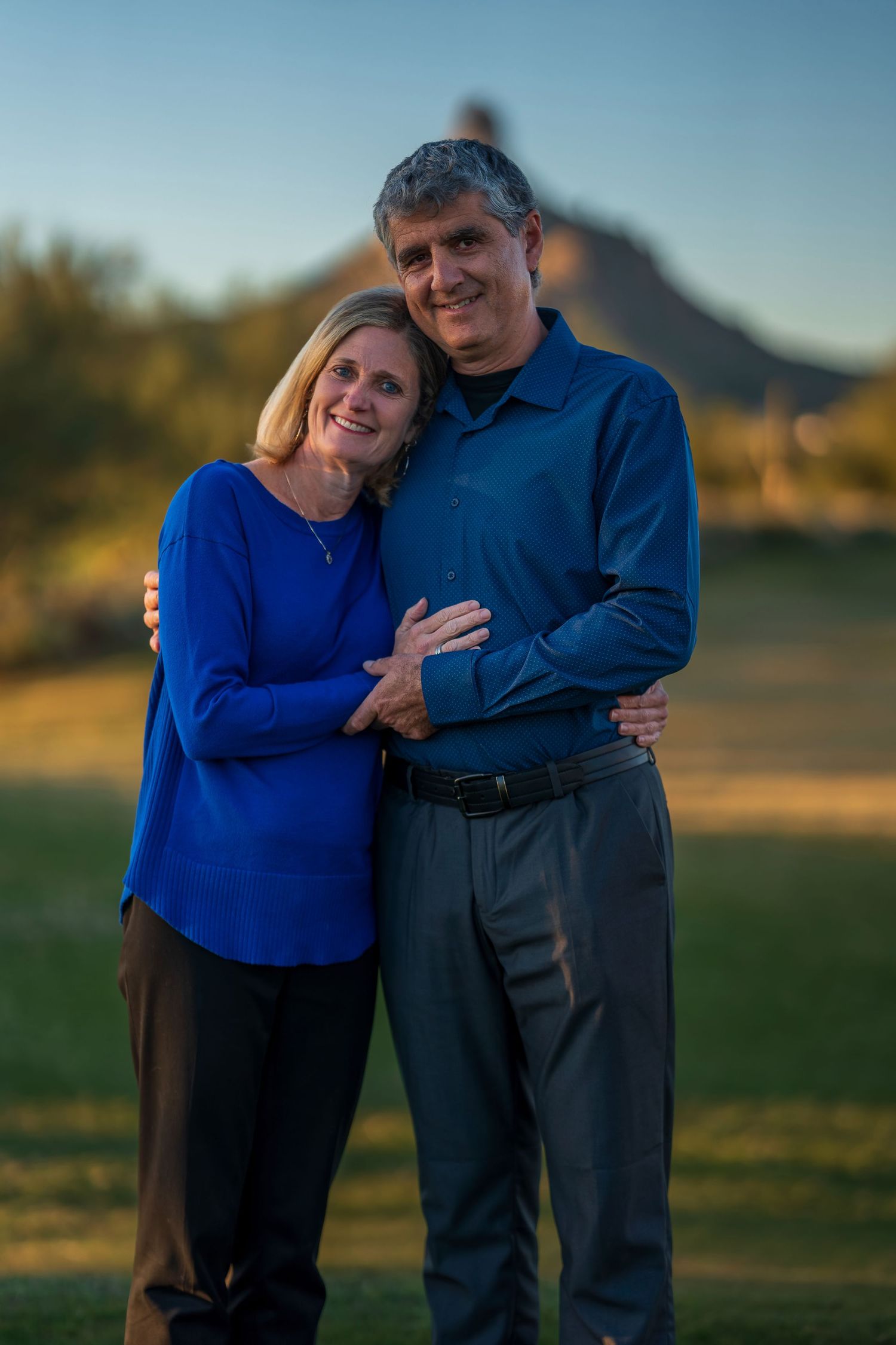 Intimate couple portrait with woman in blue sweater embracing partner outdoors.