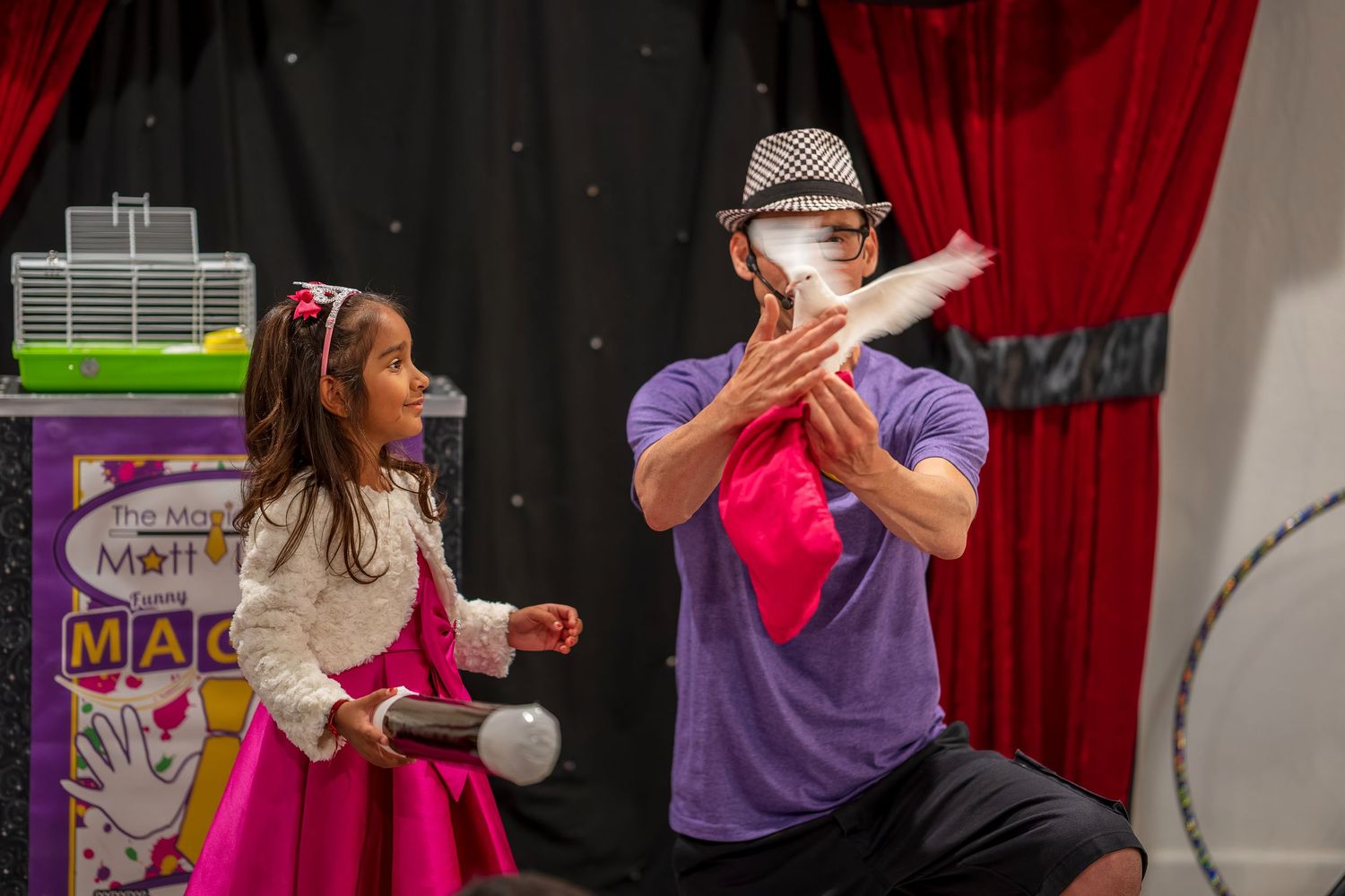 Magic show performance with red curtain backdrop and stage lighting.