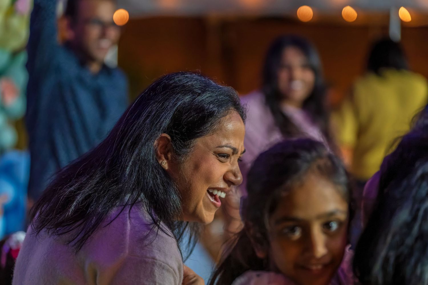 People dancing and celebrating at a lively party with warm lighting and festive decorations.
