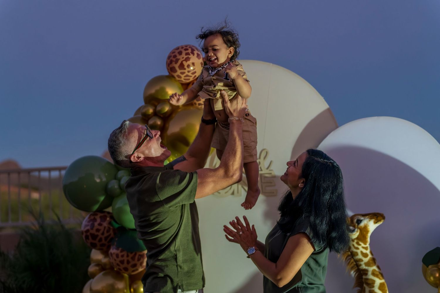Joyful outdoor celebration scene at sunset with balloons and decorative elements.