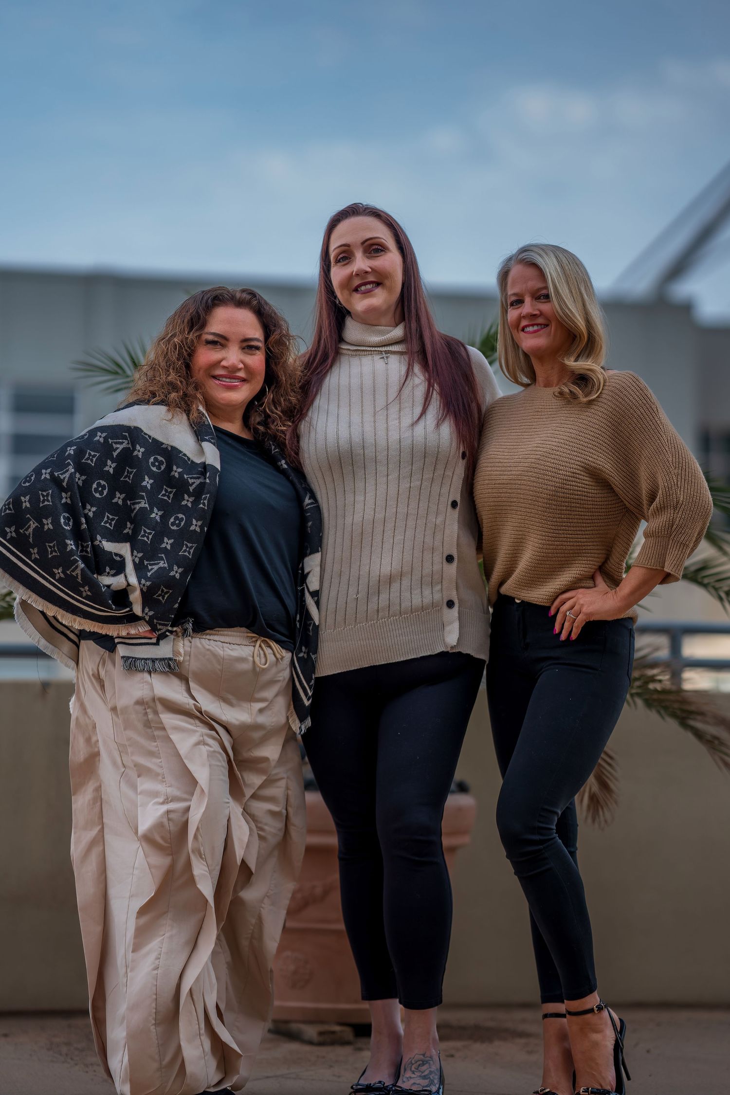 Friends in autumn attire sharing laughs during outdoor photoshoot.