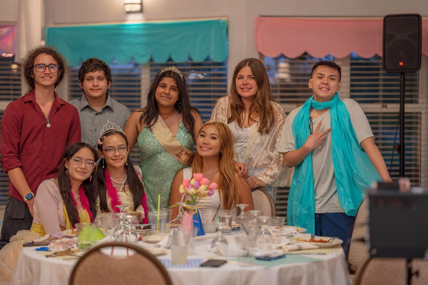 A group of people seated at decorated tables during a celebratory event with colorful decor.