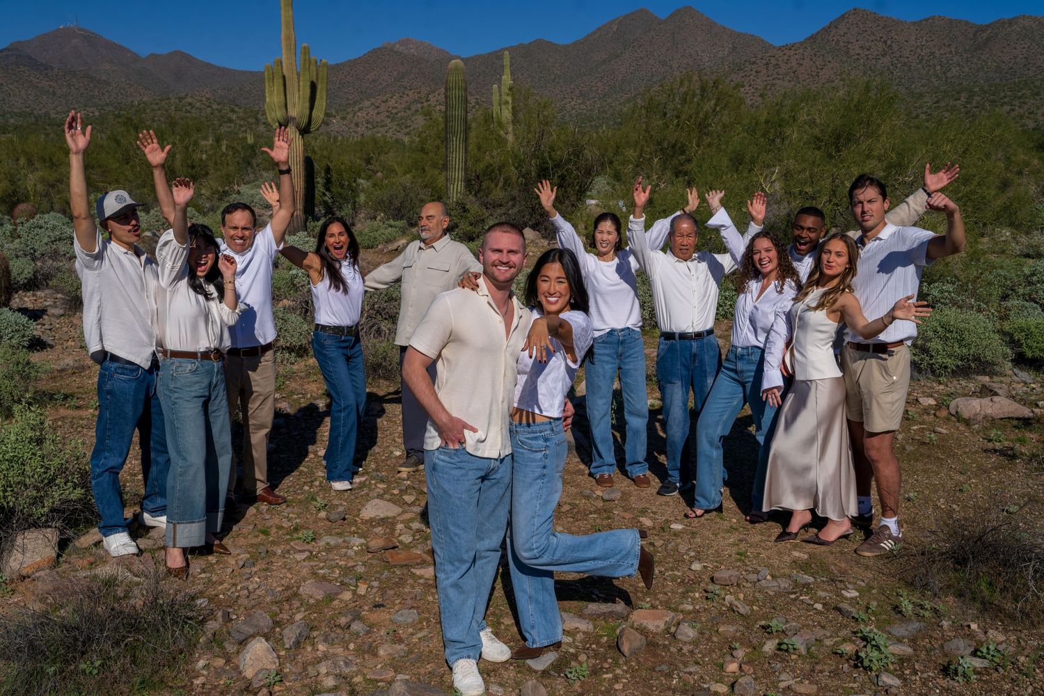 Group celebration photo in natural desert setting with mountains in background.
