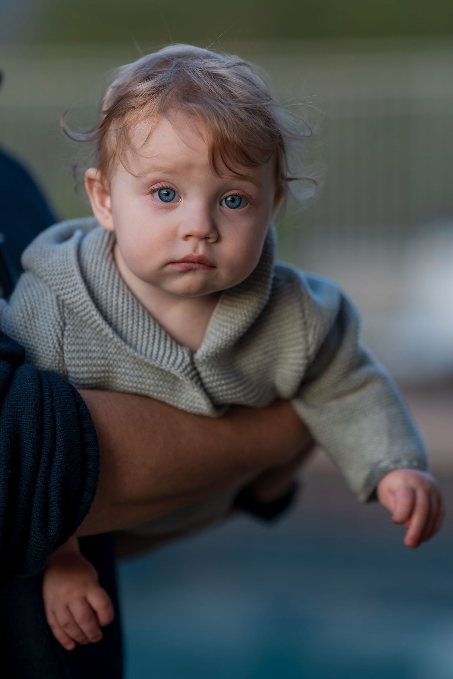 Close up portrait of a baby wearing a gray sweater.