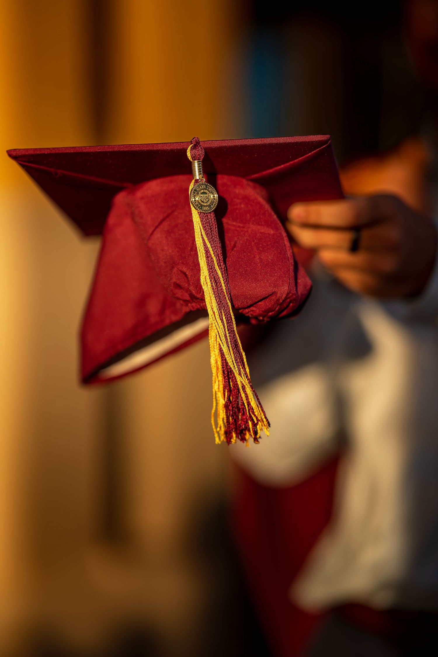 Detail shot of maroon graduation cap tassel against dark background.
