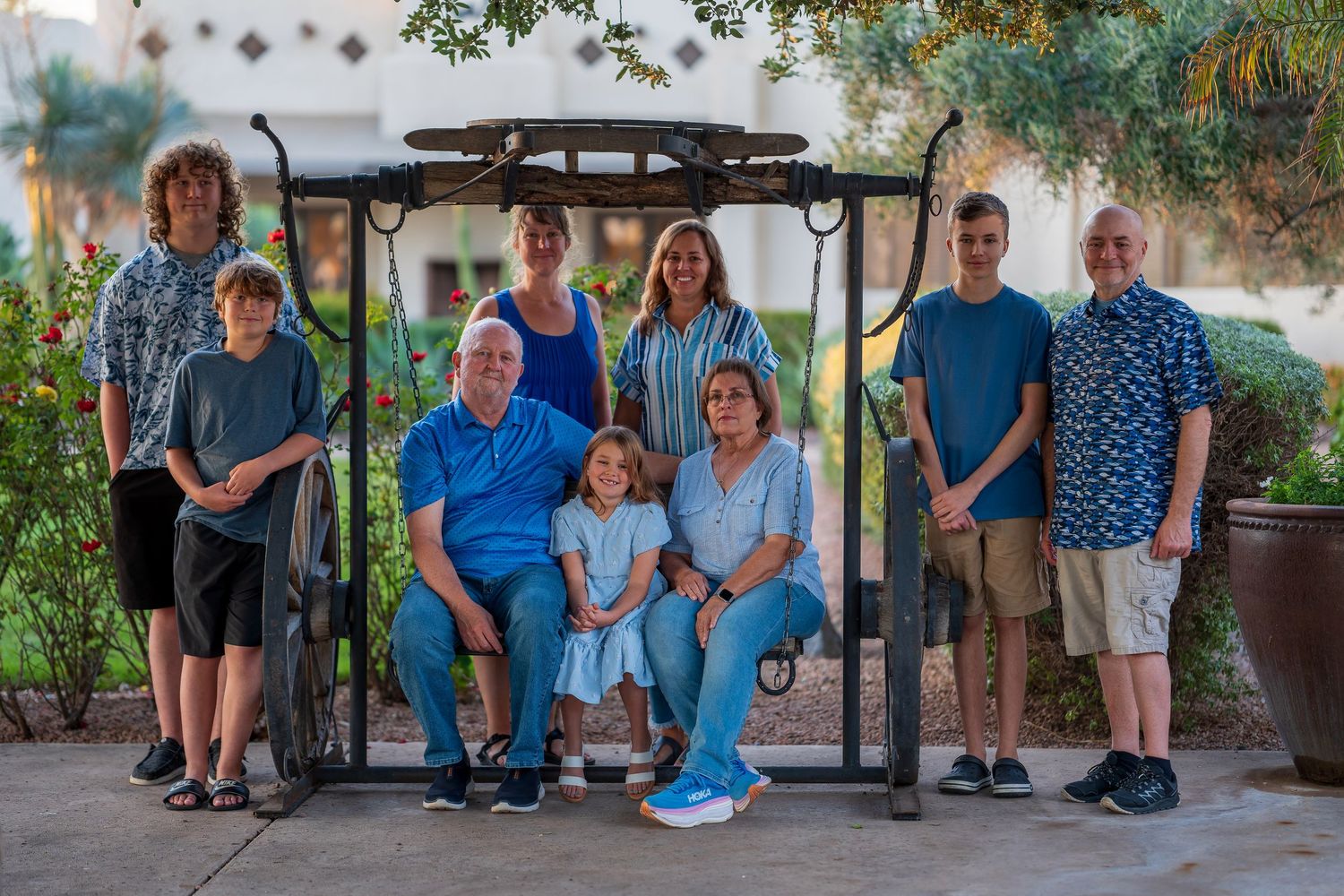 Family group photo session outdoors with everyone wearing coordinated blue and white outfits.