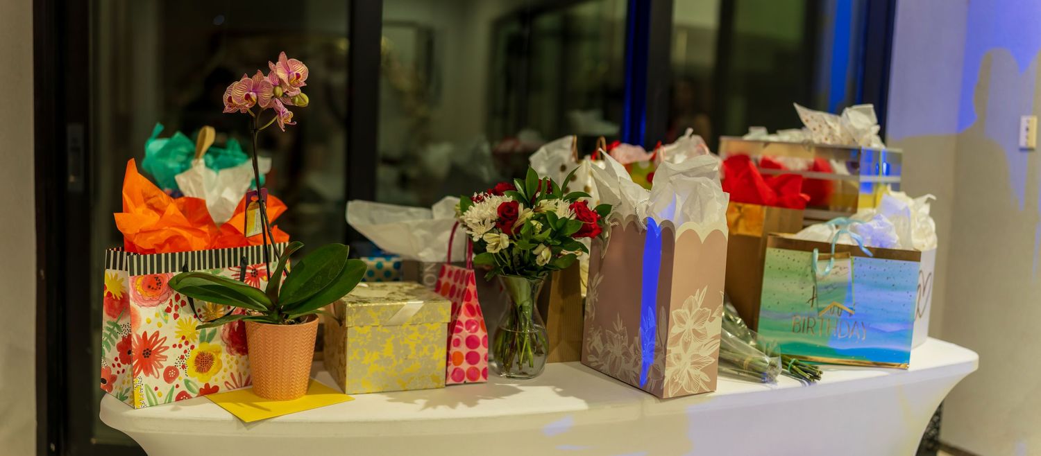 Party setup with gifts and decorations displayed on white tables.