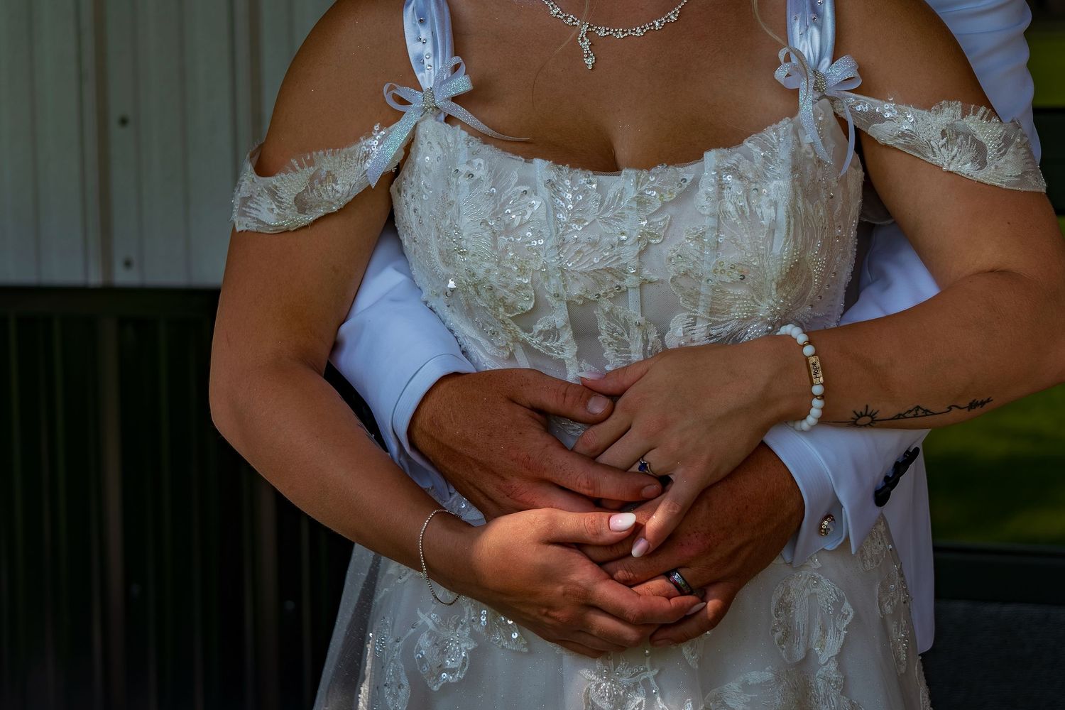 Bride in white lace dress with delicate necklace and blue accents.