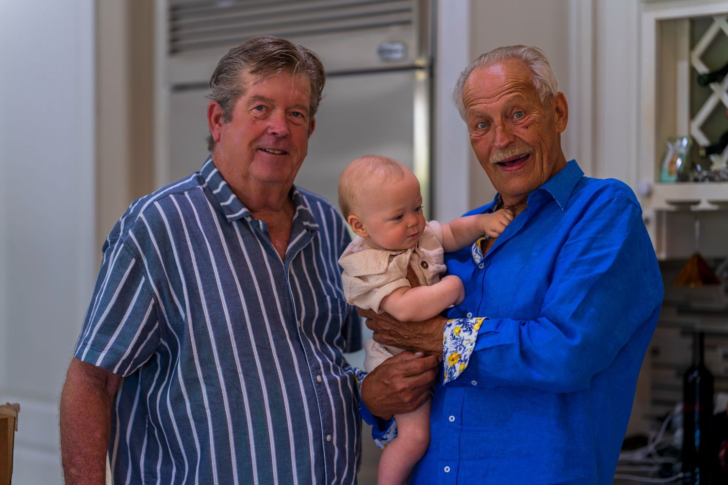 Three generations gather in a kitchen for a family moment.