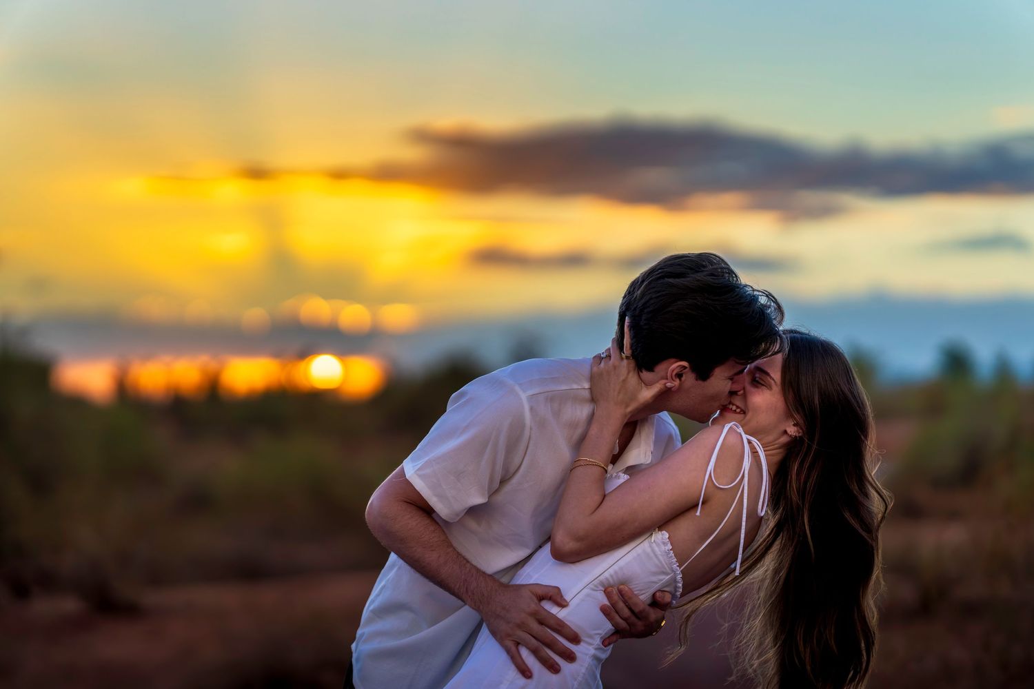 An intimate moment between a couple during their sunset desert engagement session.