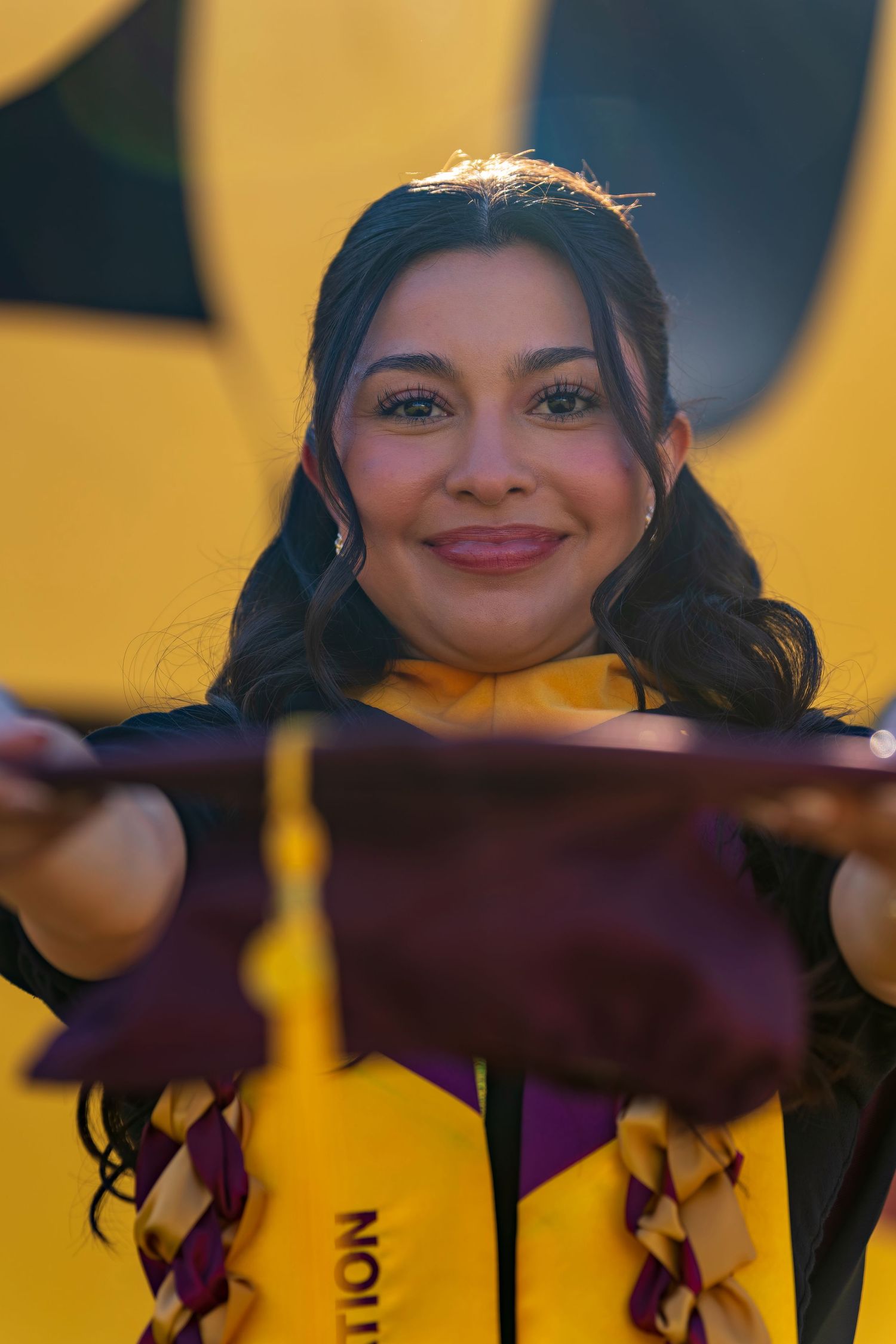 Graduate peeks over maroon diploma cover with gold numbers in background.